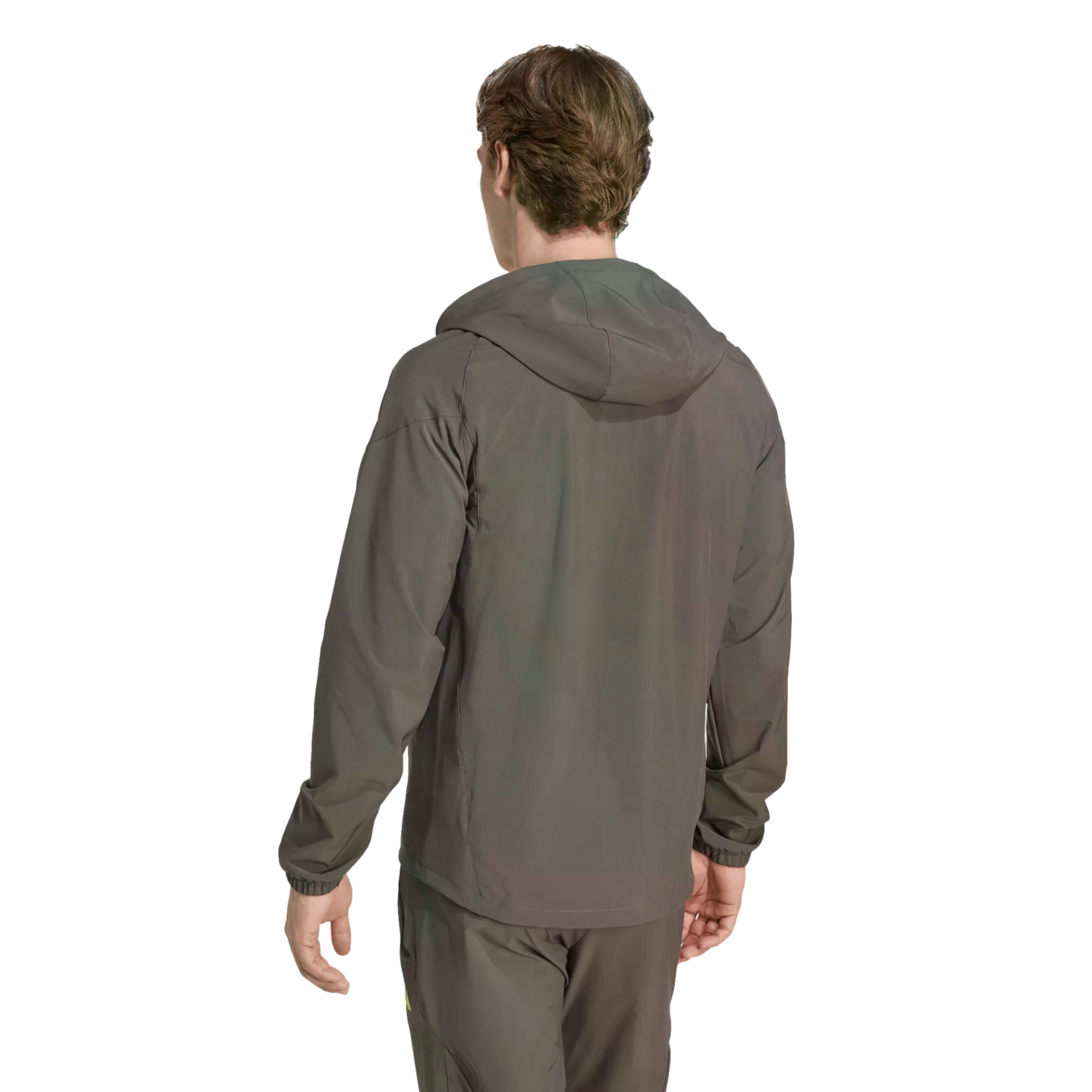 Rear view of a person in a grey hooded windbreaker and matching pants against a solid black background.