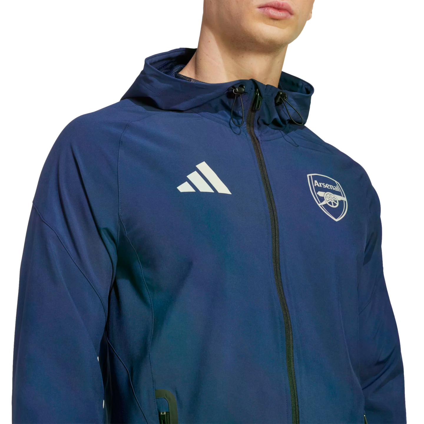 Man wearing a navy blue Adidas hooded jacket with the Arsenal football club crest and white Adidas logo, against a black background.