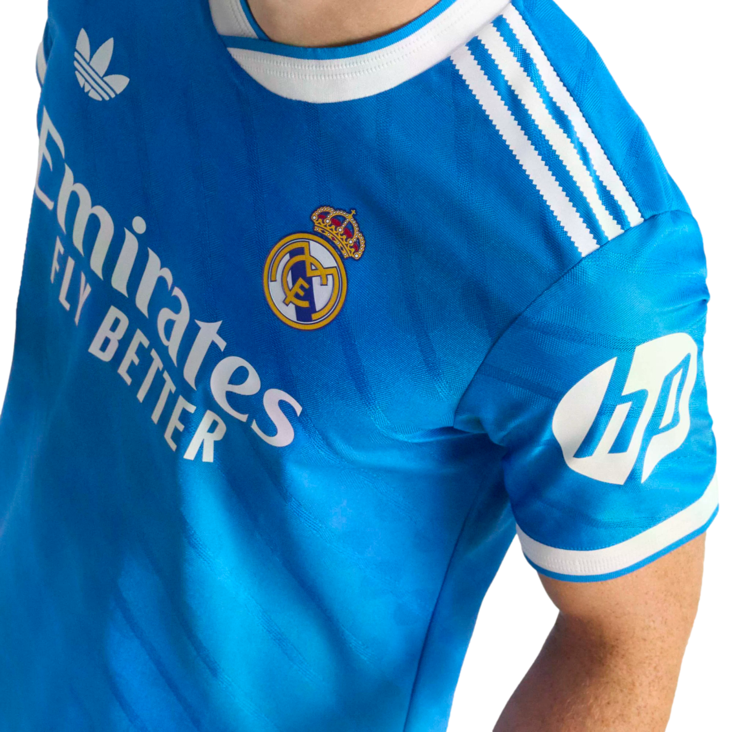 A blue Real Madrid soccer jersey with white Adidas Trefoil, Emirates, and HP logos, white shoulder stripes, and the team's crest.