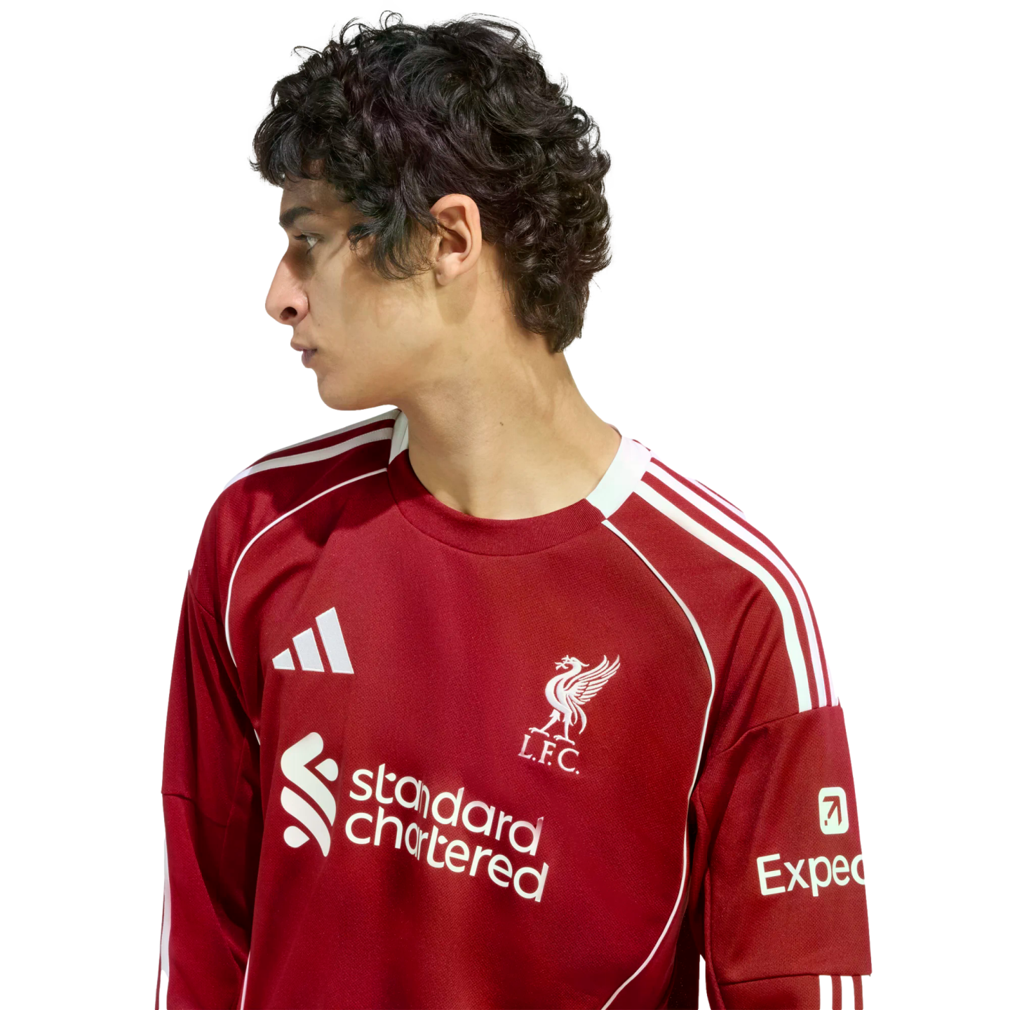 Side profile of a young man with dark, curly hair wearing a red Liverpool FC jersey against a solid black background.