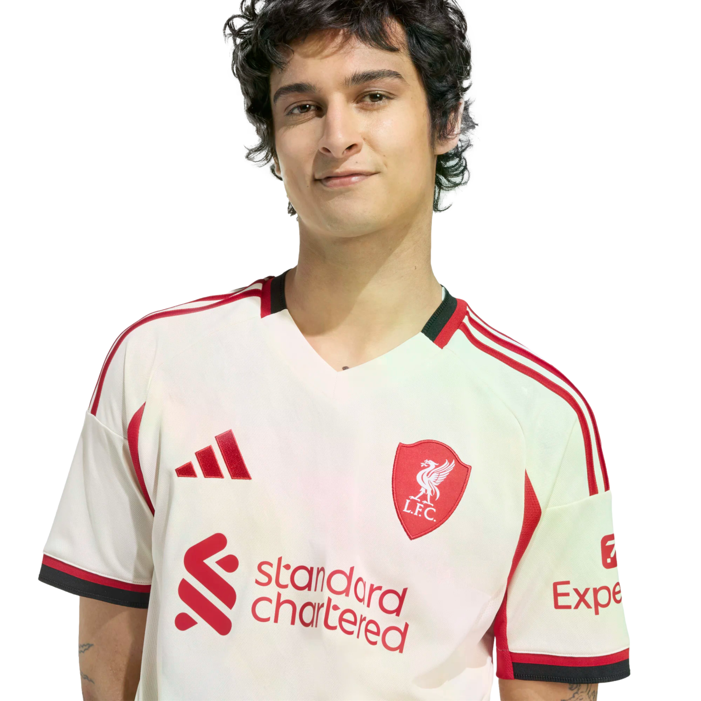 A young man with dark wavy hair wearing a white and red Liverpool FC soccer jersey, smiling against a plain black background.