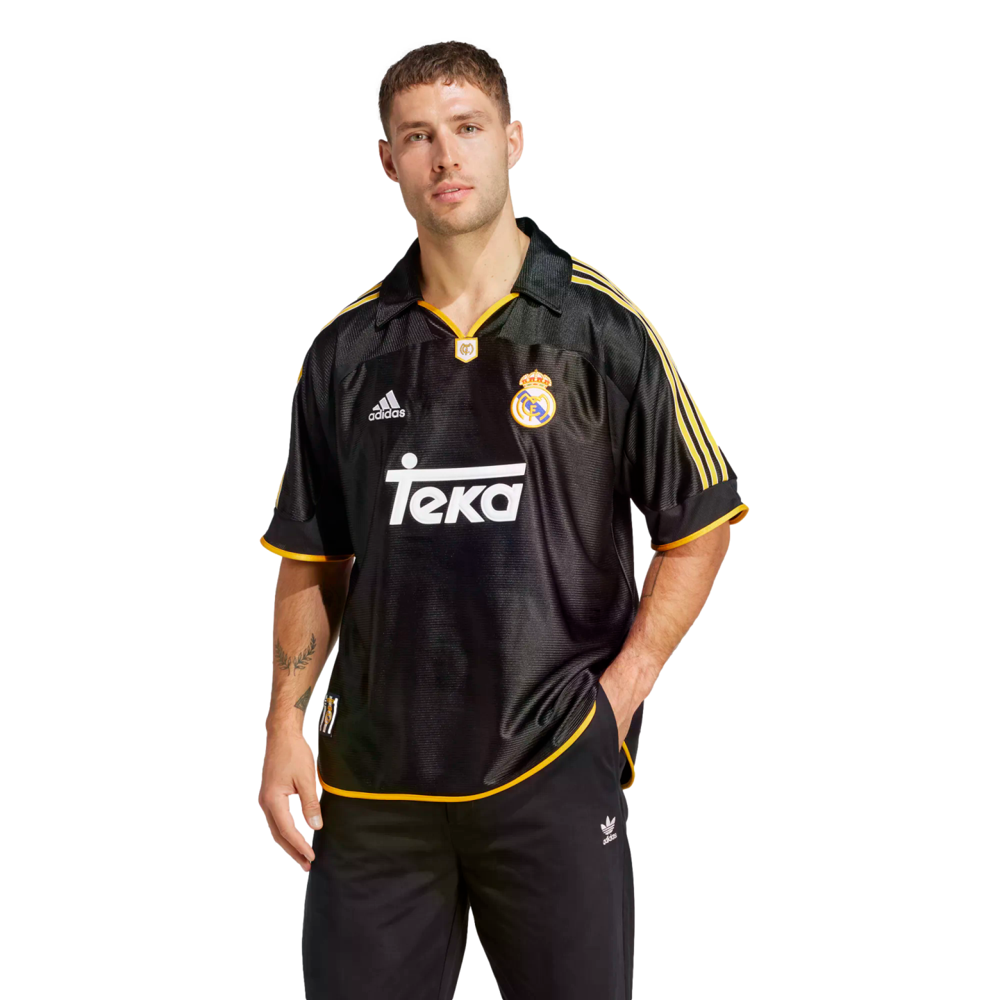 A man modeling a black and gold retro Adidas Real Madrid soccer jersey with a white Teka sponsor logo across the chest.