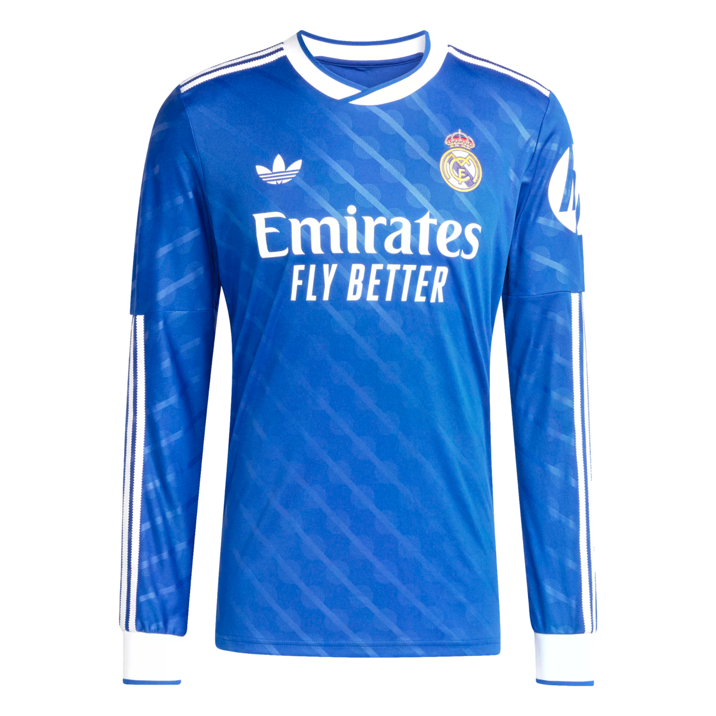 Long-sleeved blue Real Madrid jersey with white Adidas Trefoil, team crest, and Emirates sponsor. Features white collar and cuffs with subtle tonal patterns.