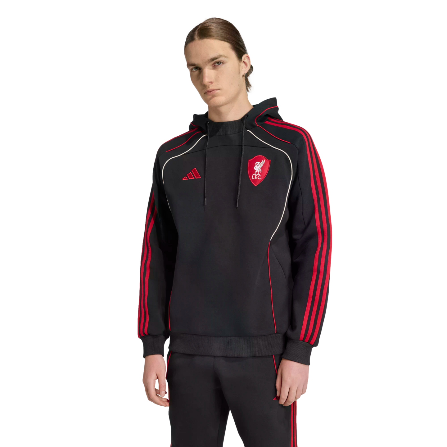 A person wears a black Adidas Liverpool F.C. hoodie with red stripes and white piping details, standing against a black background.