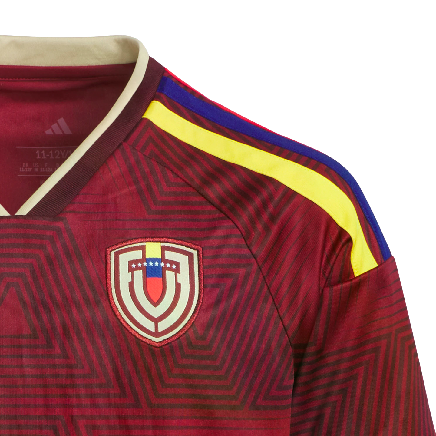 Close-up of a maroon Adidas Venezuela national soccer jersey with a geometric pattern, the team crest, and yellow and blue shoulder stripes.