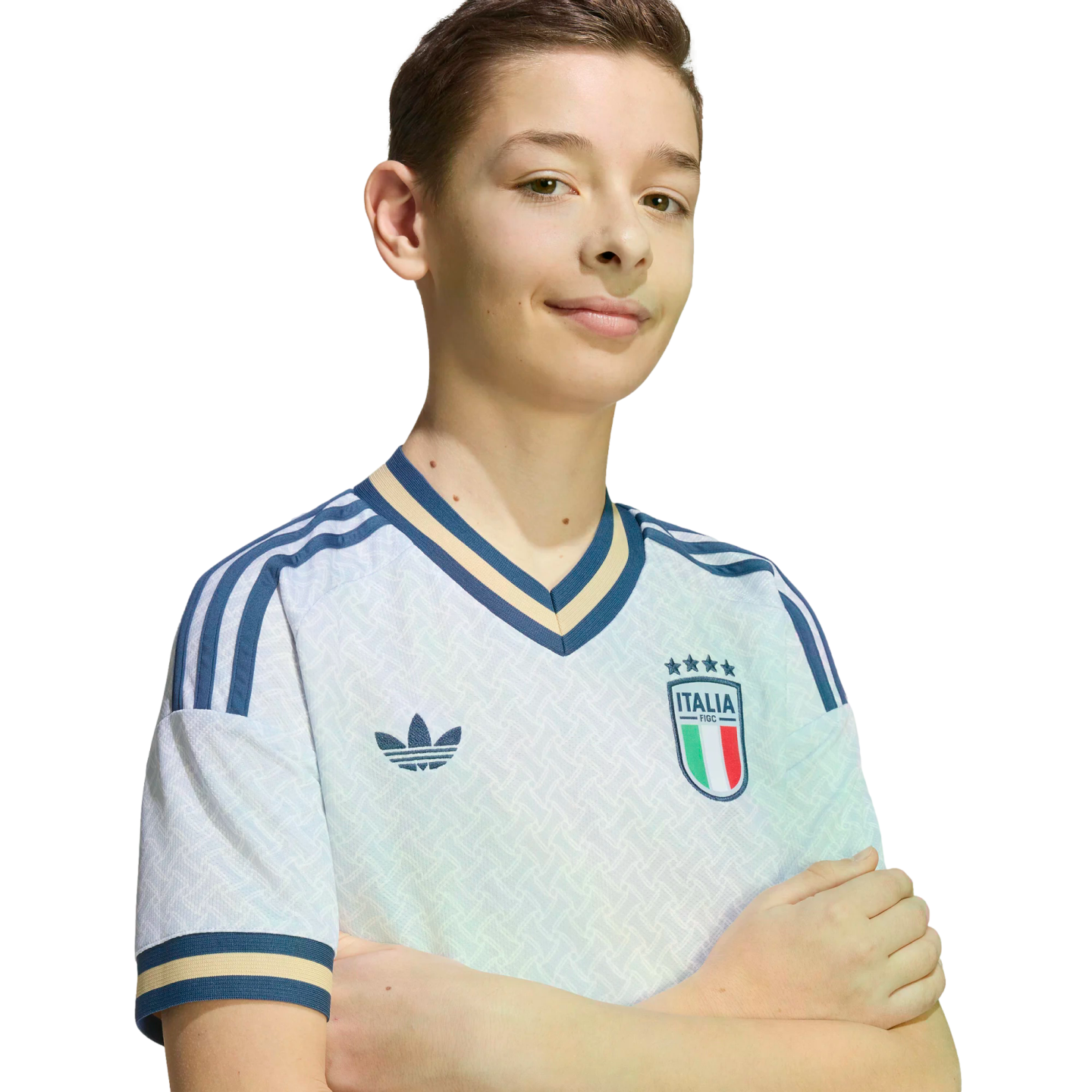 A young boy smiles with arms crossed, wearing a white Adidas Italian national soccer team jersey against a solid black background.