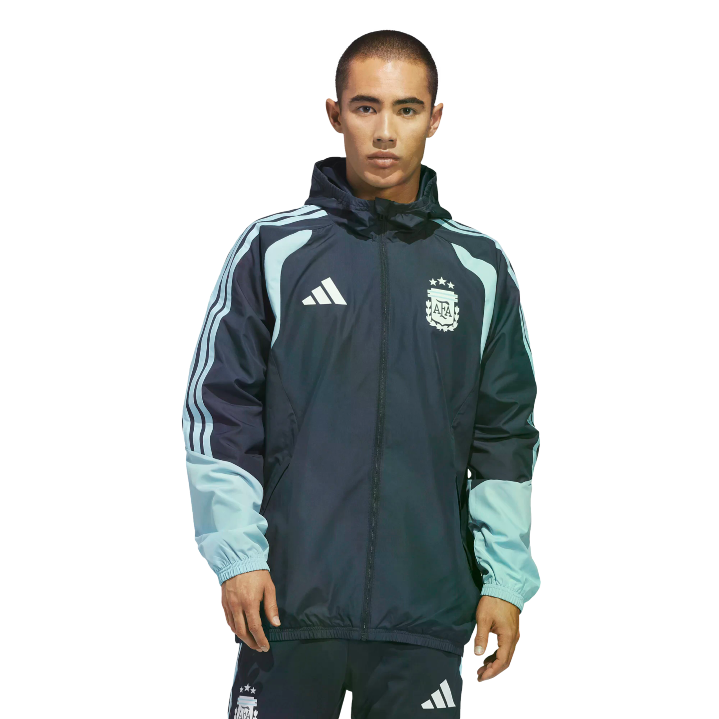 Man wearing a navy and light blue Adidas Argentina national football team windbreaker and matching pants with the AFA crest, against a black background.