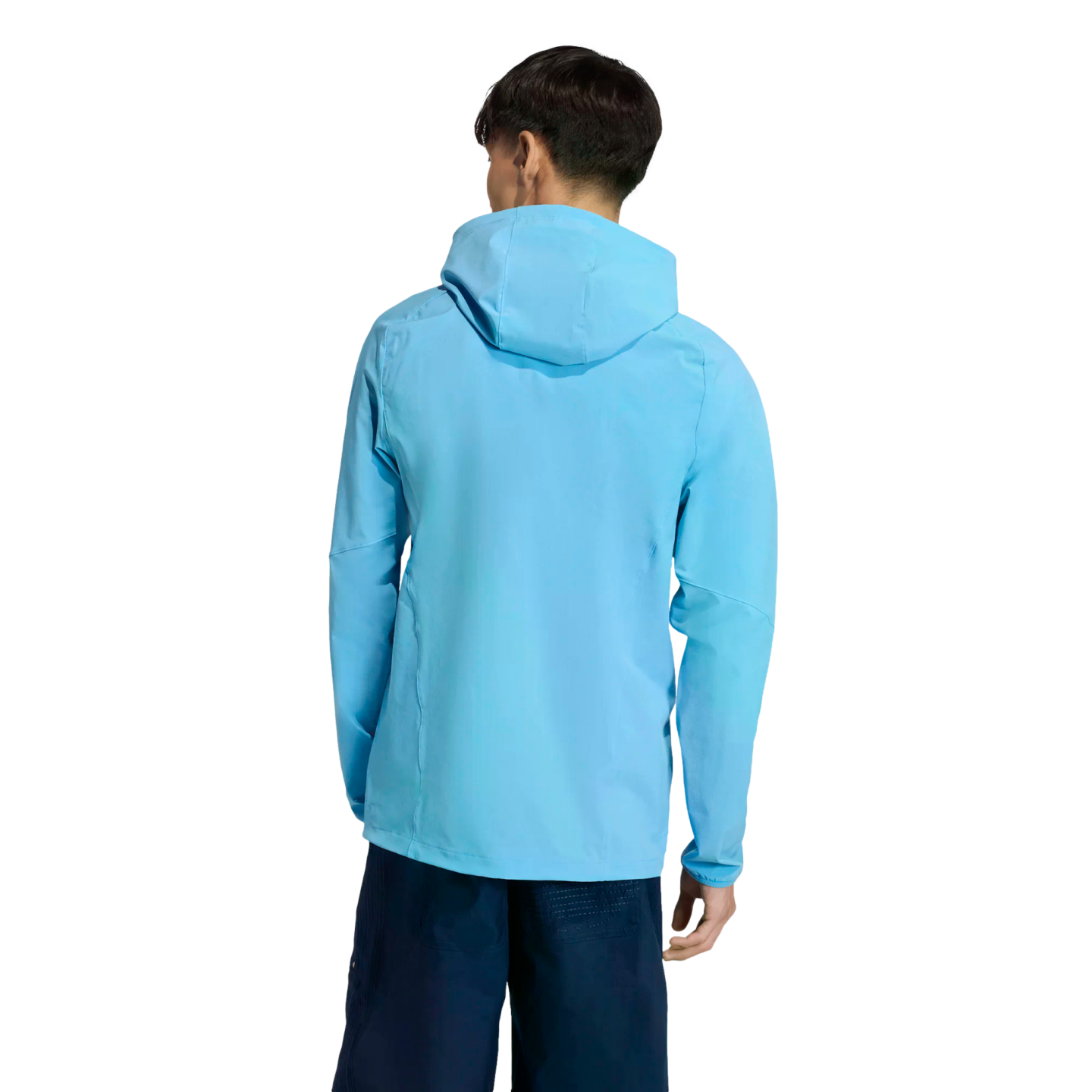Back view of a person wearing a light blue hooded jacket and dark blue shorts against a solid black background.