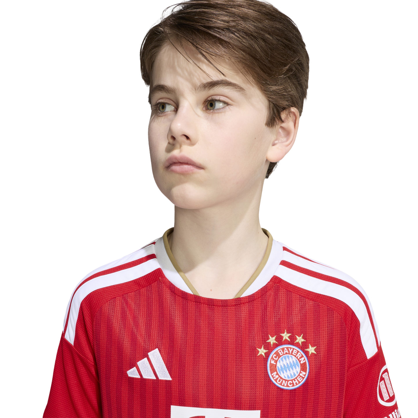 A young boy looking to the side while wearing a red and white FC Bayern Munich soccer jersey against a plain white background.