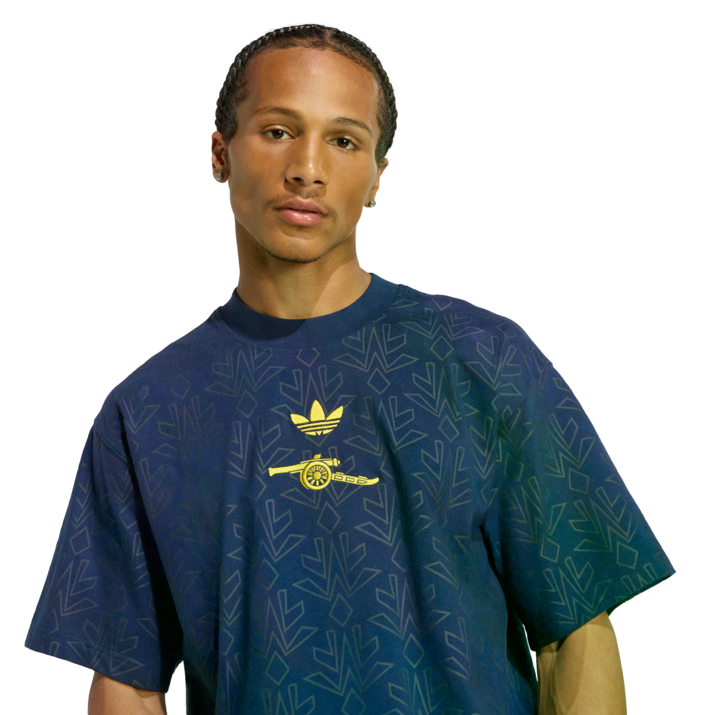 A man wears a dark blue t-shirt with yellow Adidas and Arsenal logos. The shirt features an all-over geometric pattern, and the background is solid black.