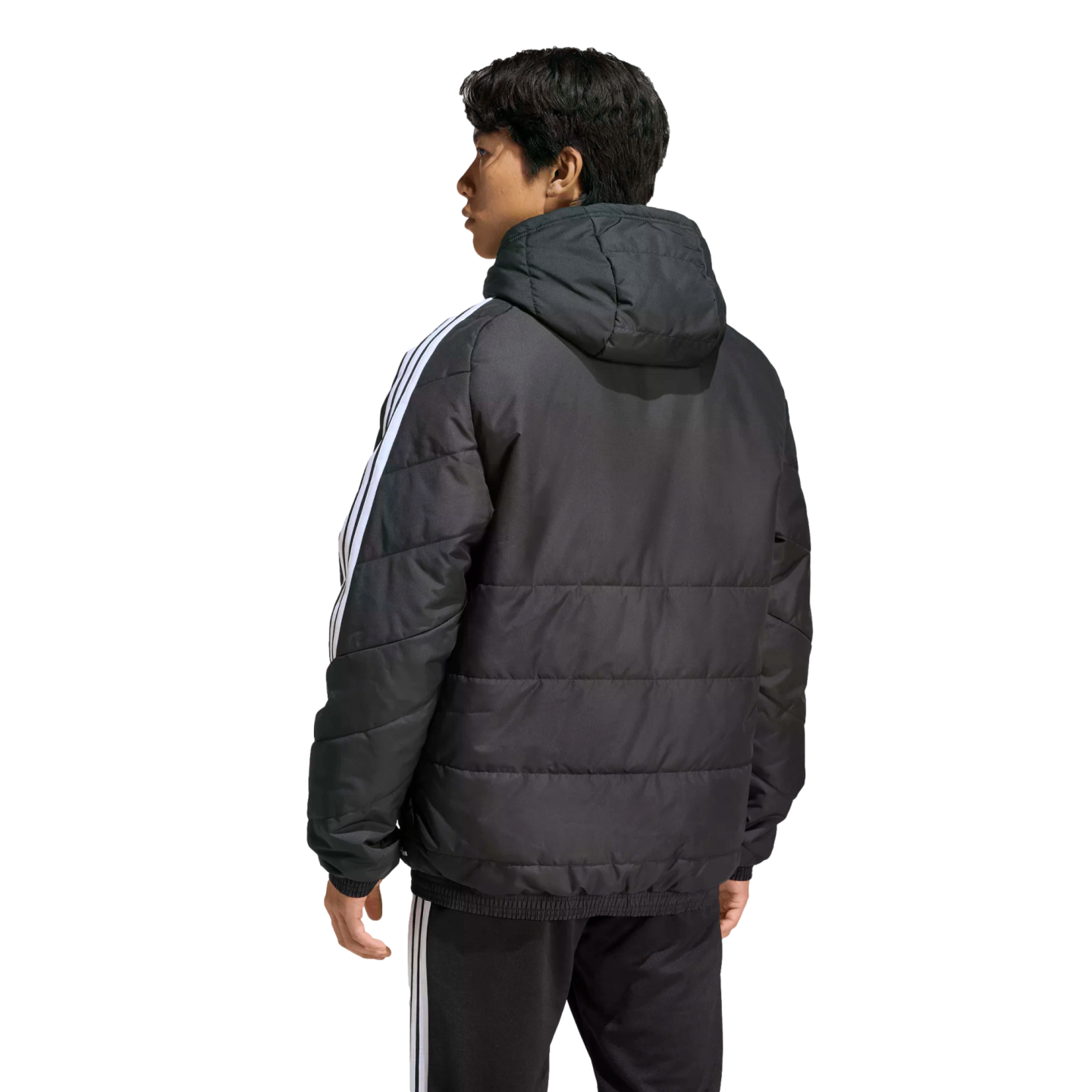 Rear view of a man wearing a black hooded puffer jacket and matching pants with white stripes, standing against a solid black background.