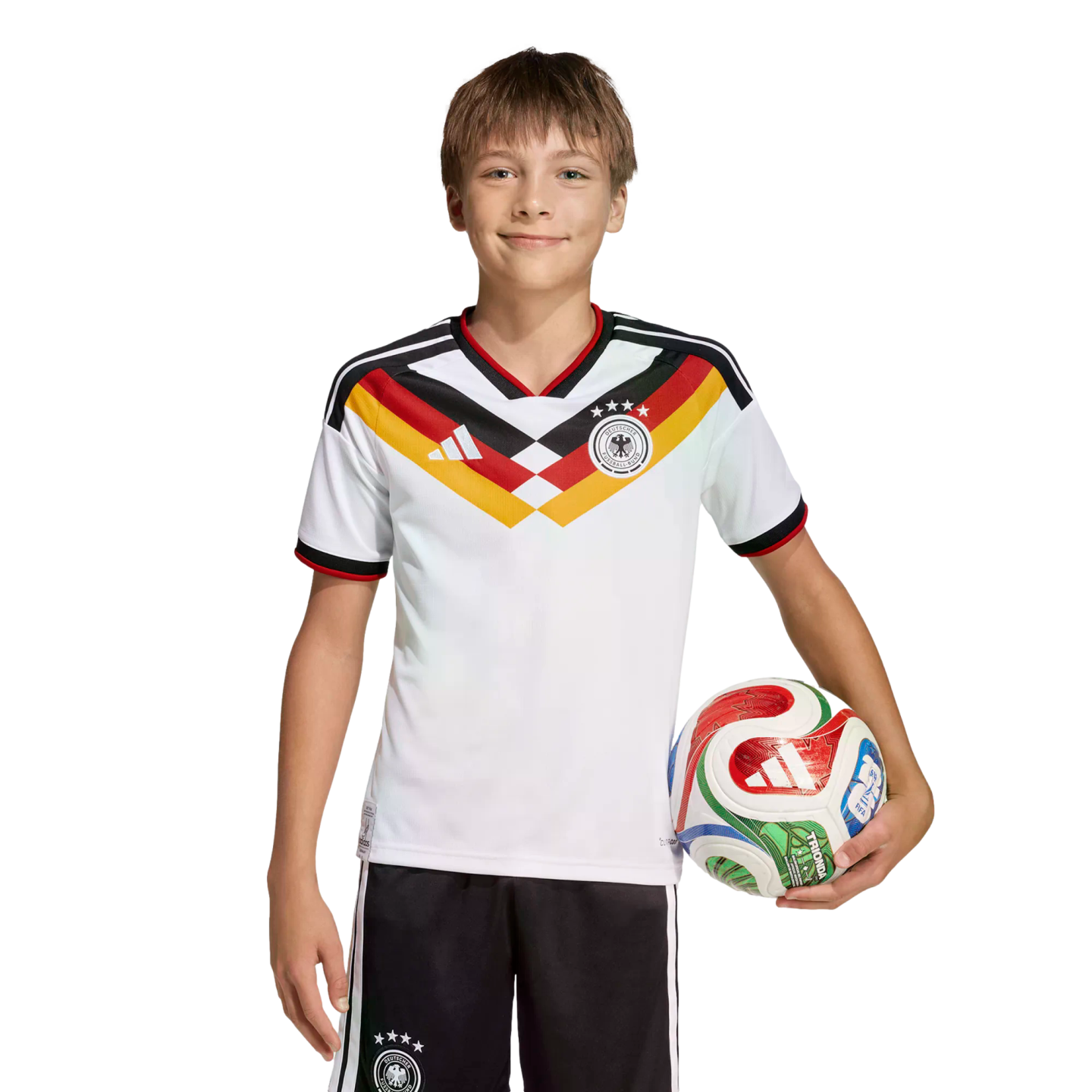 A smiling boy in a German national soccer uniform holds a colorful soccer ball against a black background.