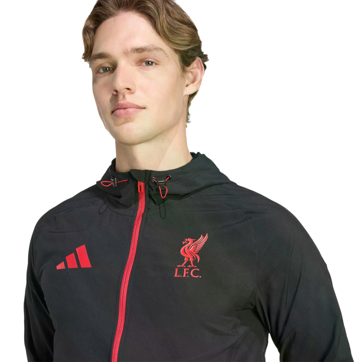 A man wearing a black Adidas zip-up hoodie featuring a red Liverpool FC crest and red Adidas logo on the chest.