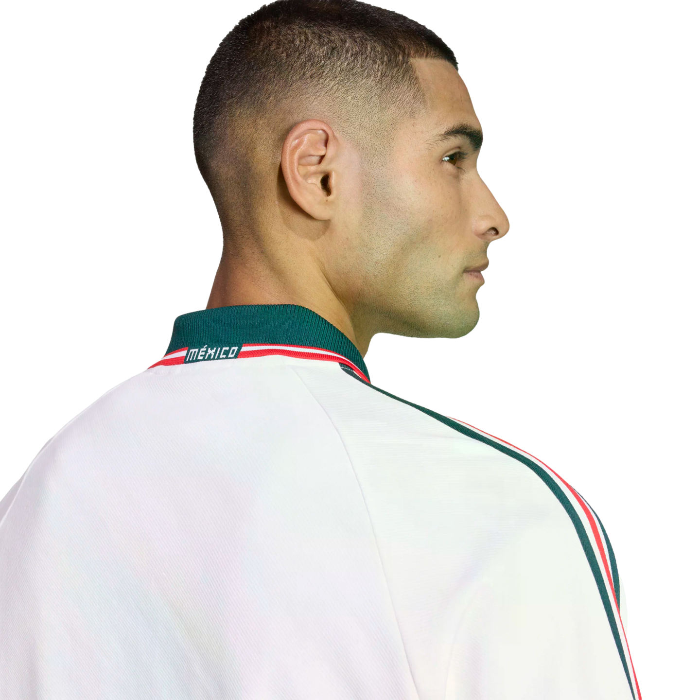 Profile of a man with a buzz cut wearing a white Mexico jacket with green and red trim, set against a black background.