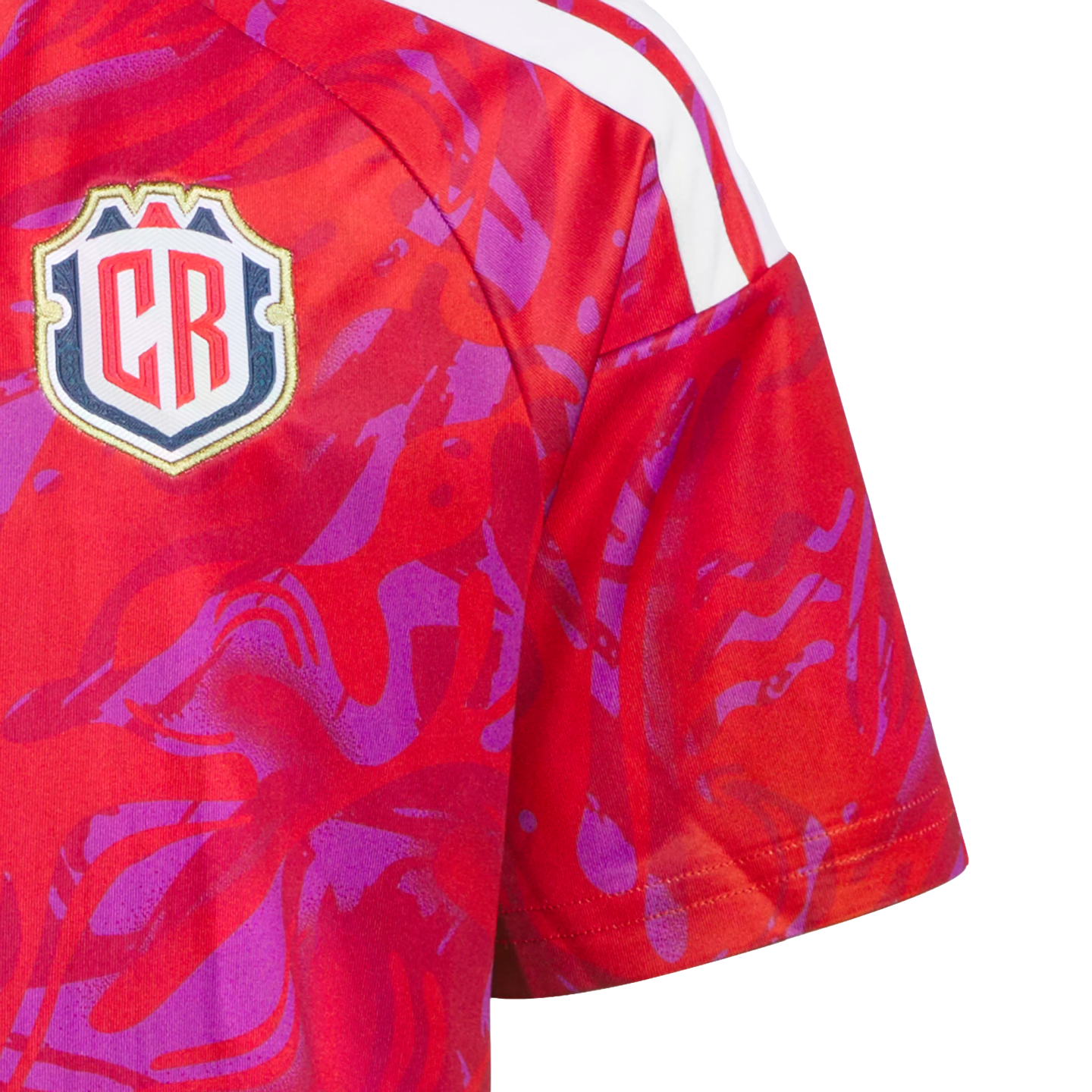 Close-up of a red sports jersey with a purple abstract pattern, white shoulder stripes, and a shield-shaped crest featuring the letters "CR".