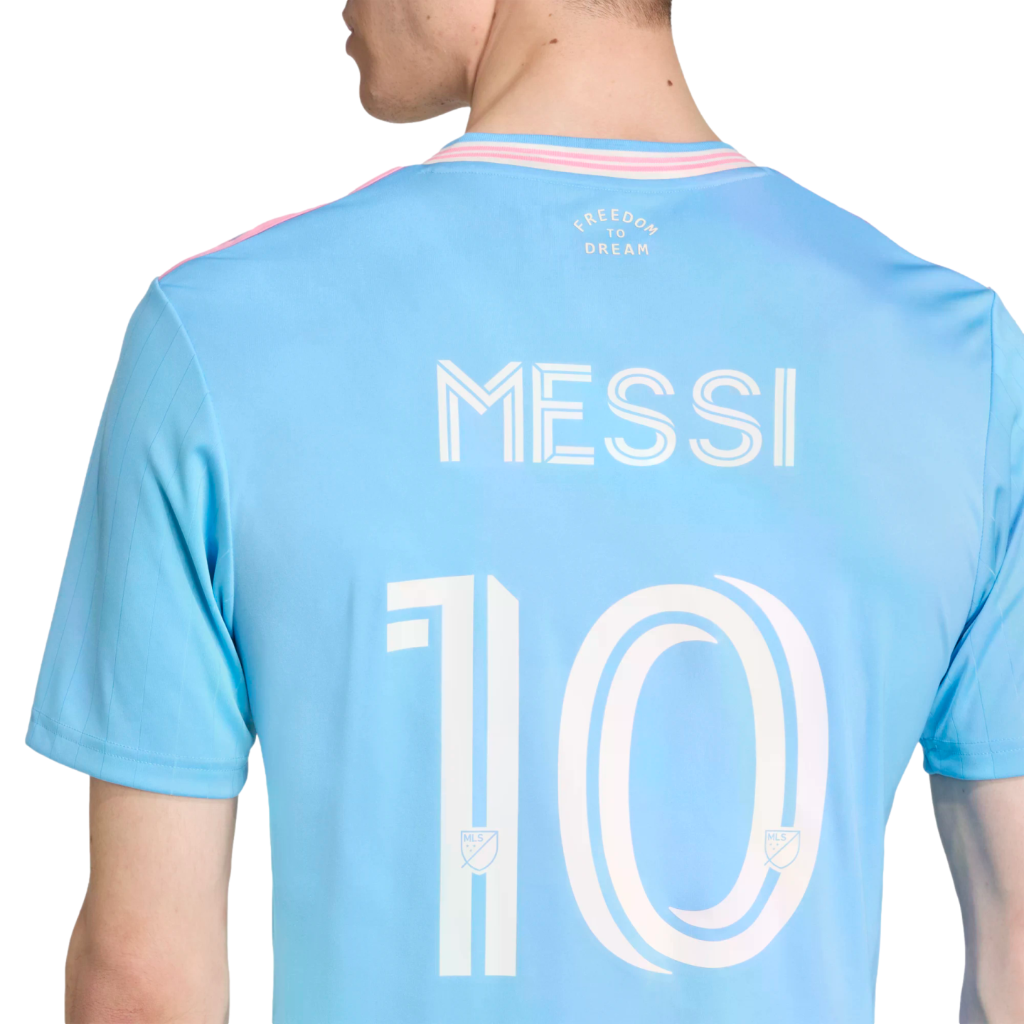 Back of a light blue soccer jersey with "MESSI" and "10" in white. It features pink trim and the words "FREEDOM TO DREAM" printed on the upper back.