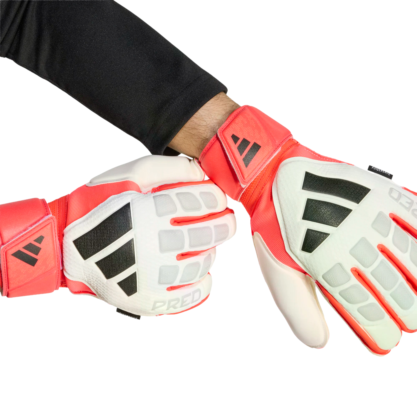 A person wears red, white, and black Adidas Predator goalkeeper gloves against a solid black background. One hand is clenched in a fist, and the other is open.