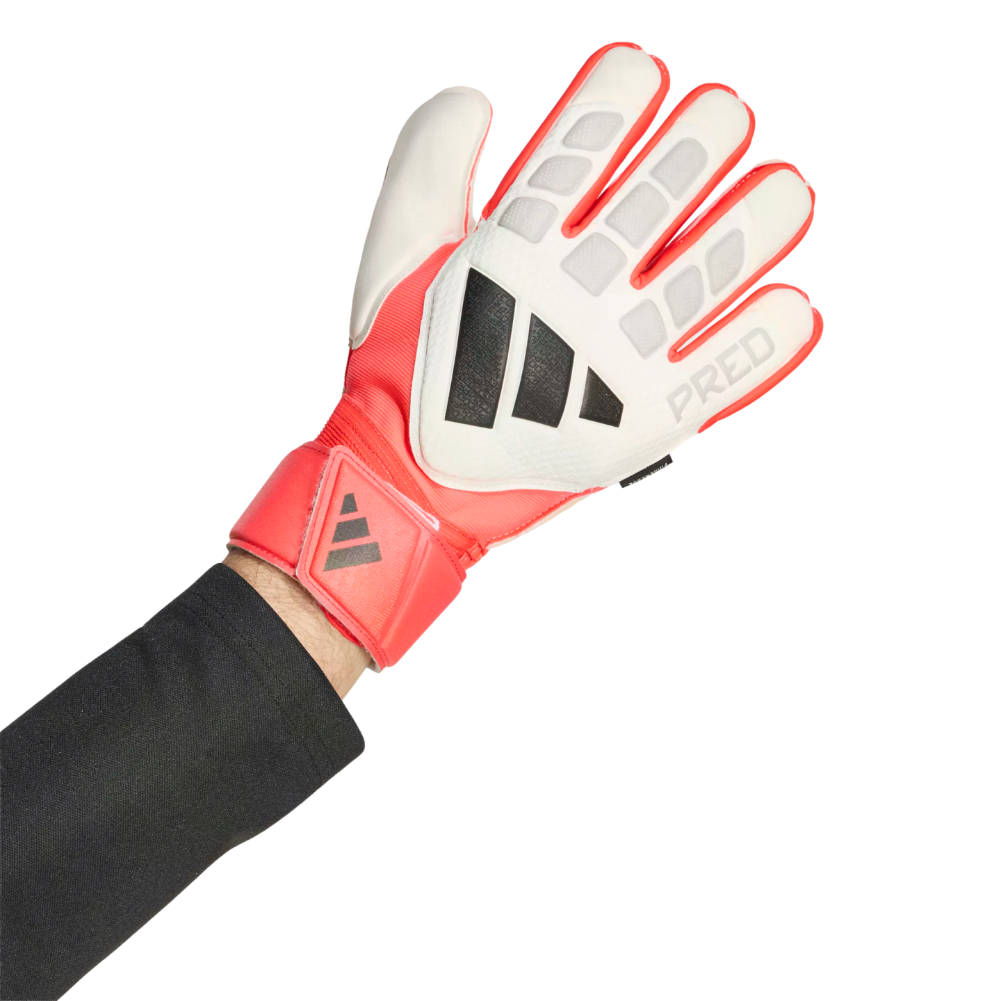A person wearing a white, coral red, and black Adidas Predator goalkeeper glove against a black background.