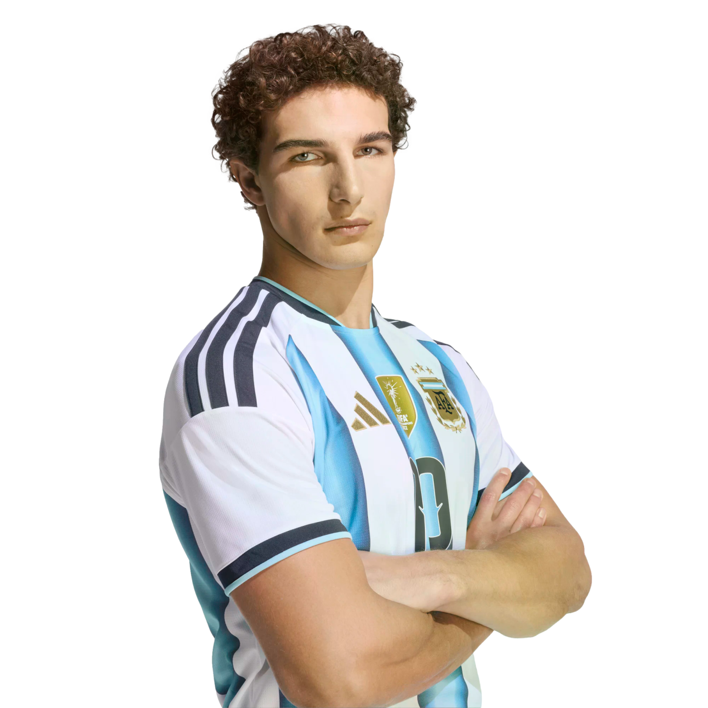 A man with curly brown hair wearing an Argentina national football team jersey, posing with arms crossed against a black background.