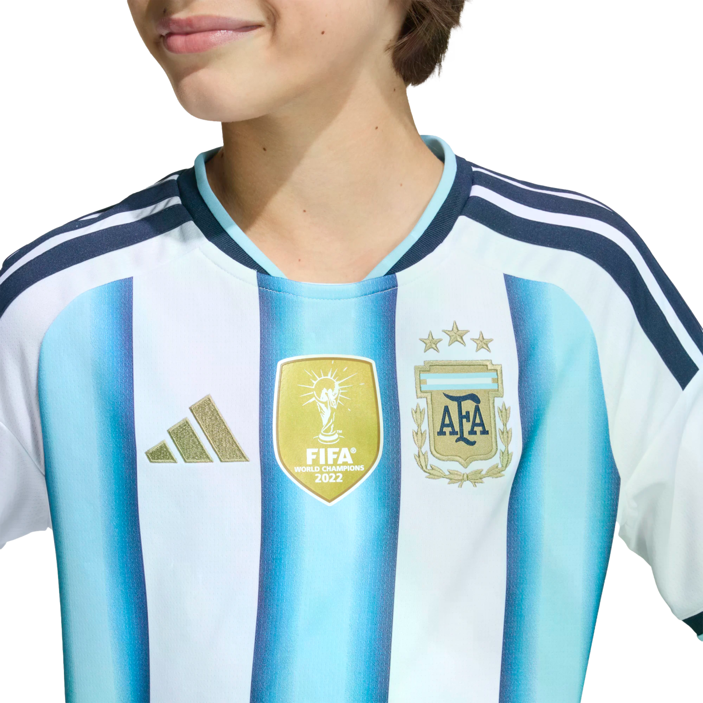 Close-up of an Argentina soccer jersey with a gold FIFA World Champions 2022 patch, three-star team crest, and gold Adidas logo.