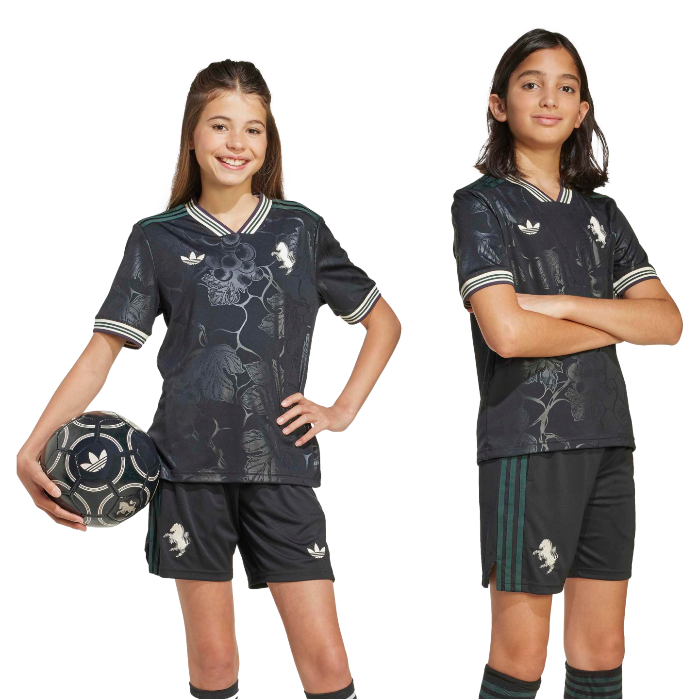 Two children wearing matching black soccer kits with subtle floral patterns and green details. One child holds a soccer ball.