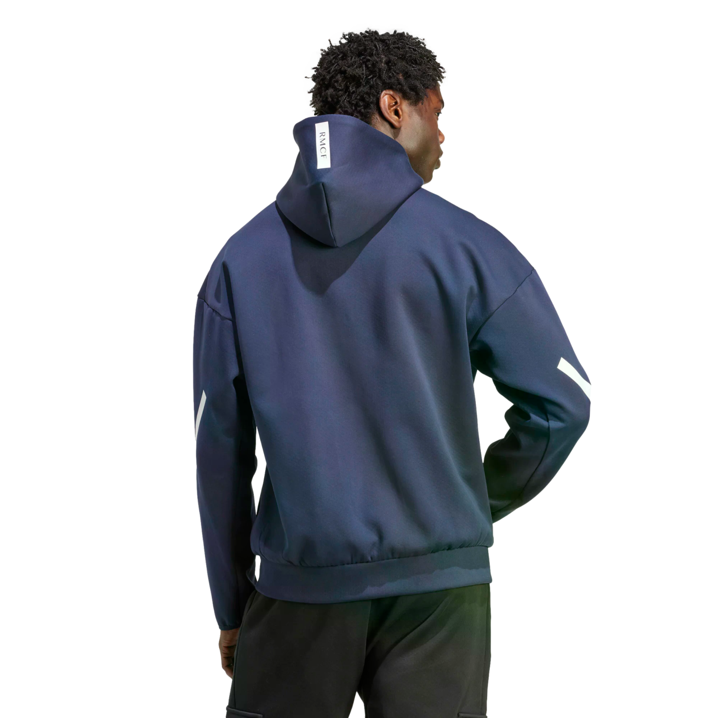 Back view of a person in a navy blue hoodie with white sleeve stripes and a small "RMCF" tag on the hood, wearing black pants.