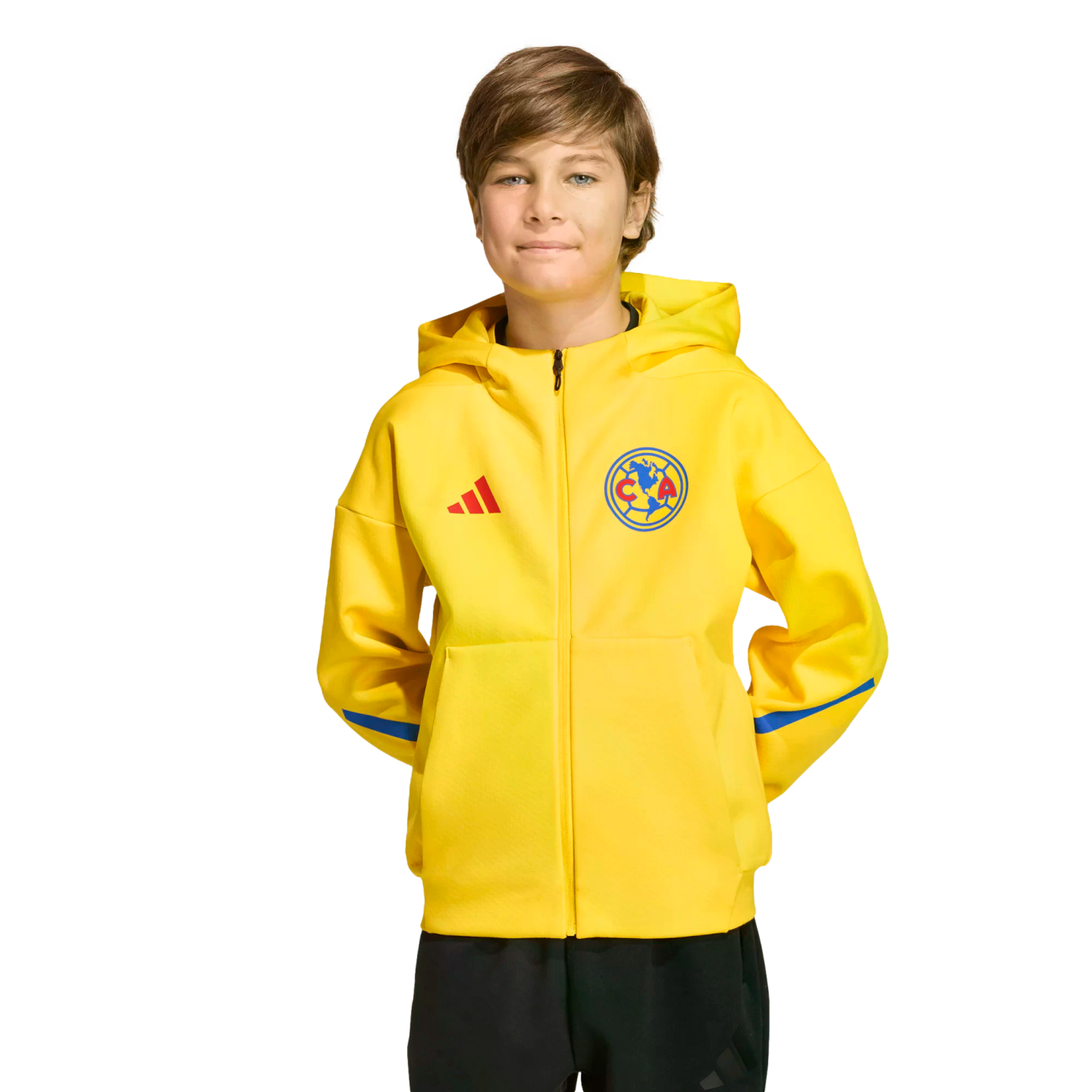 A boy wearing a yellow Club América adidas zip-up hoodie and black pants against a black background.
