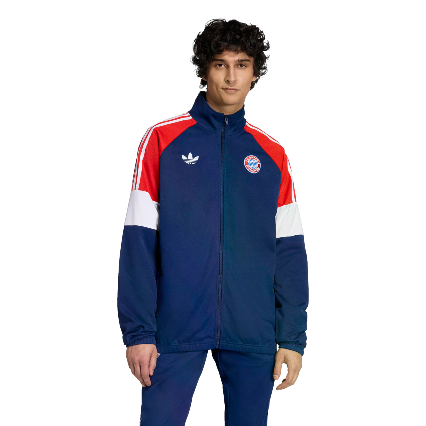 Man in a navy blue, red, and white Adidas Bayern Munich tracksuit featuring the club crest and trefoil logo, against a black background.