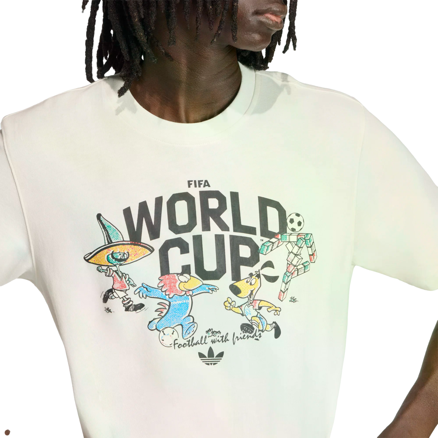 Person wearing a white Adidas FIFA World Cup t-shirt with classic mascots and the phrase "Football with friends" against a black background.
