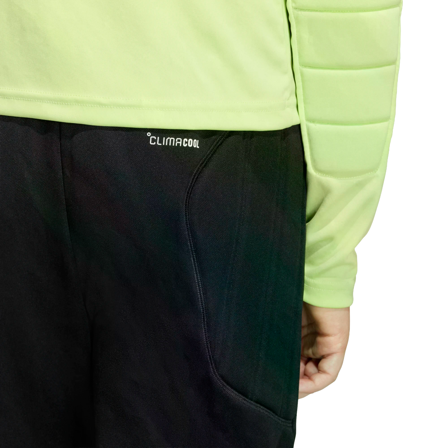 Close-up of a person wearing a lime green long-sleeved padded shirt and black pants with "CLIMACOOL" printed near the waistband against a black background.