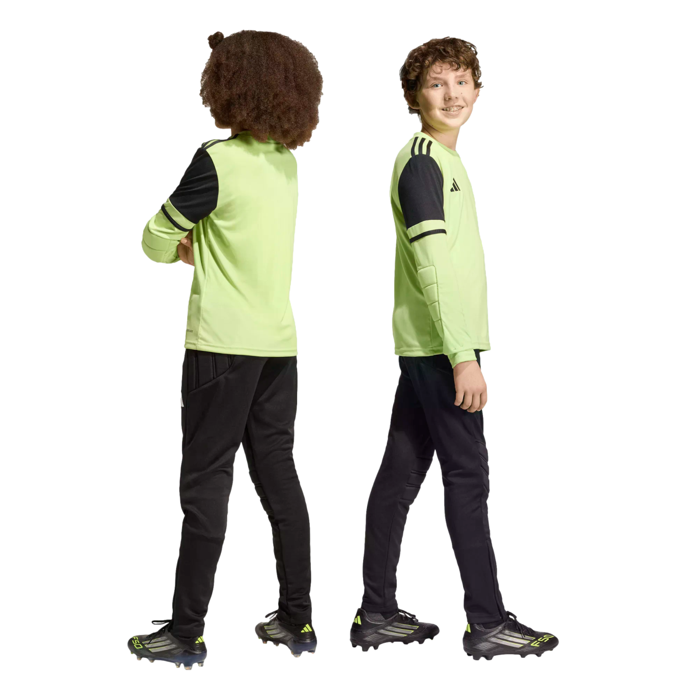 Two boys in lime green and black soccer uniforms standing back-to-back against a black background.