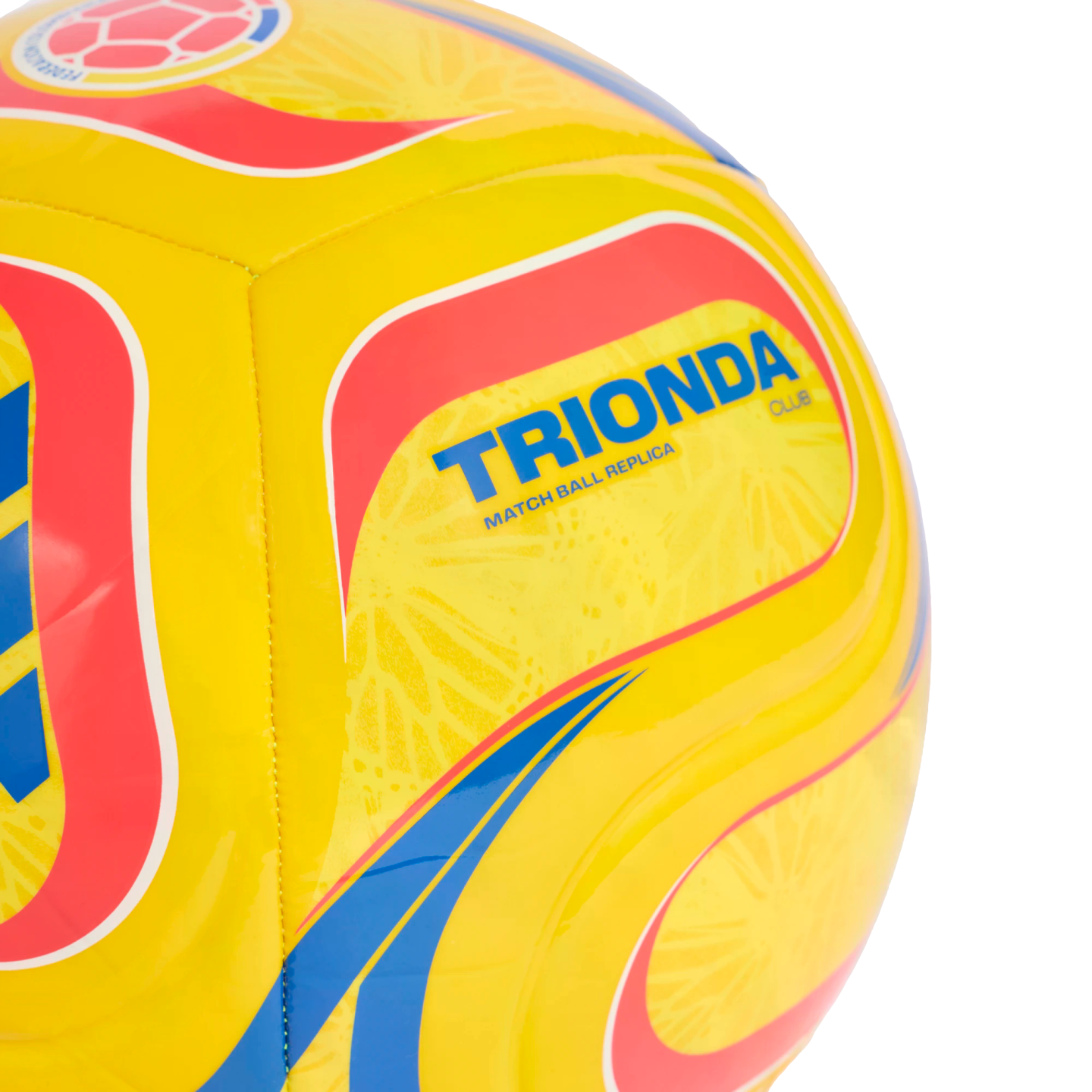 A close-up of a yellow Trionda Club replica soccer ball featuring red and blue patterns and a Colombian Football Federation logo.