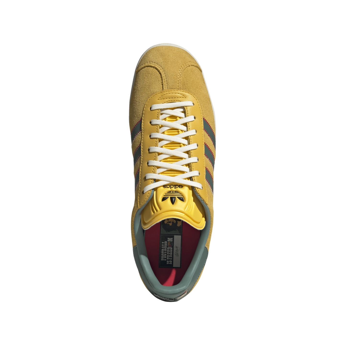Top-down view of a yellow Adidas sneaker with white laces, green and red stripes, and a red insole reading "FOOTBALL IS FREEDOM" against a black background.