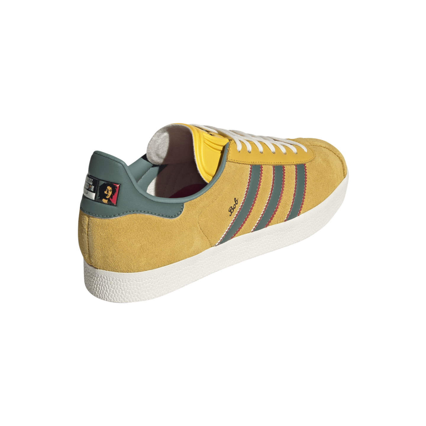 A mustard yellow suede sneaker with teal and red accents, featuring "Bob" script and a portrait on the heel tab, presented against a black background.
