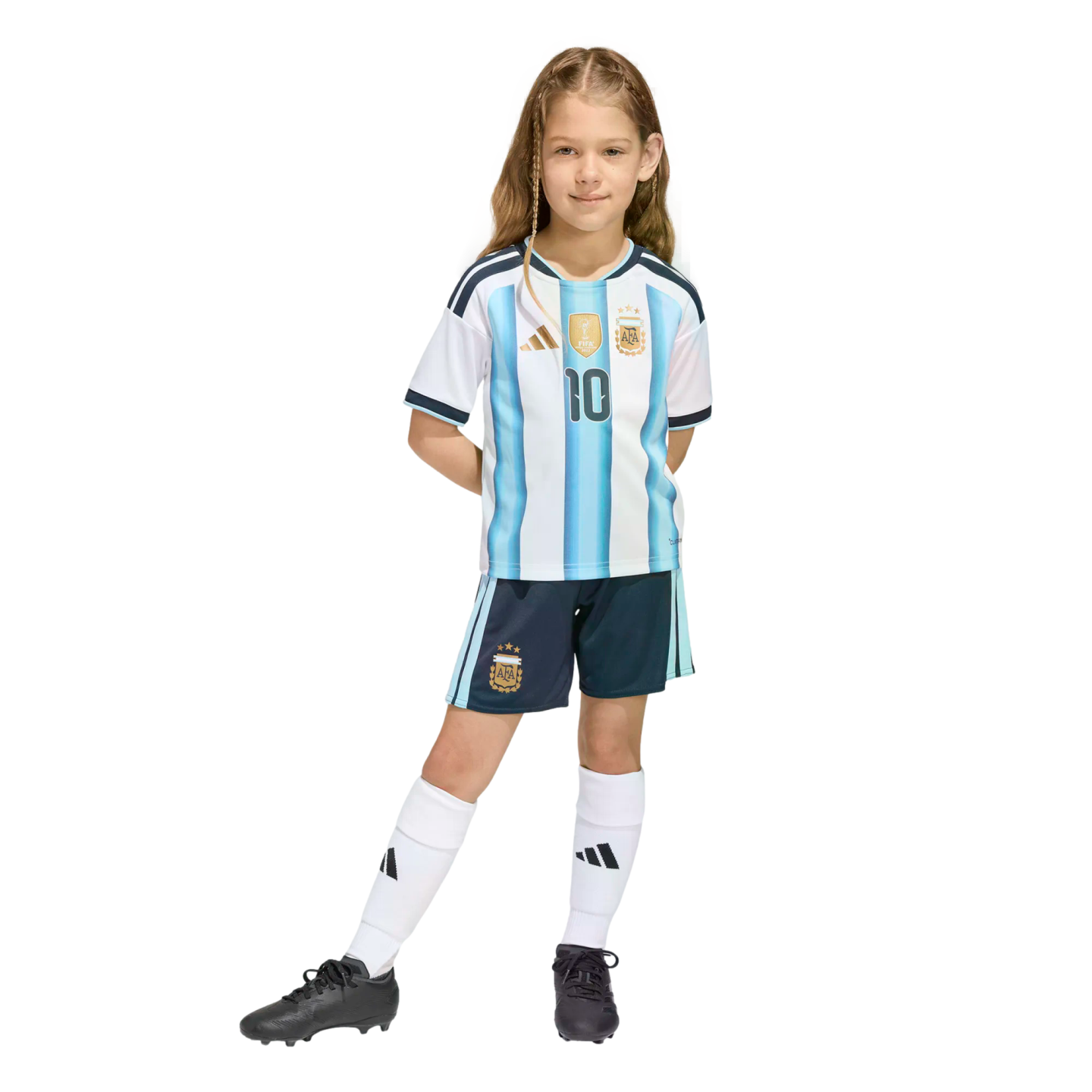 A young girl with braided hair posing in a full Argentina national football team kit, including a #10 jersey, navy shorts, white socks, and black cleats.