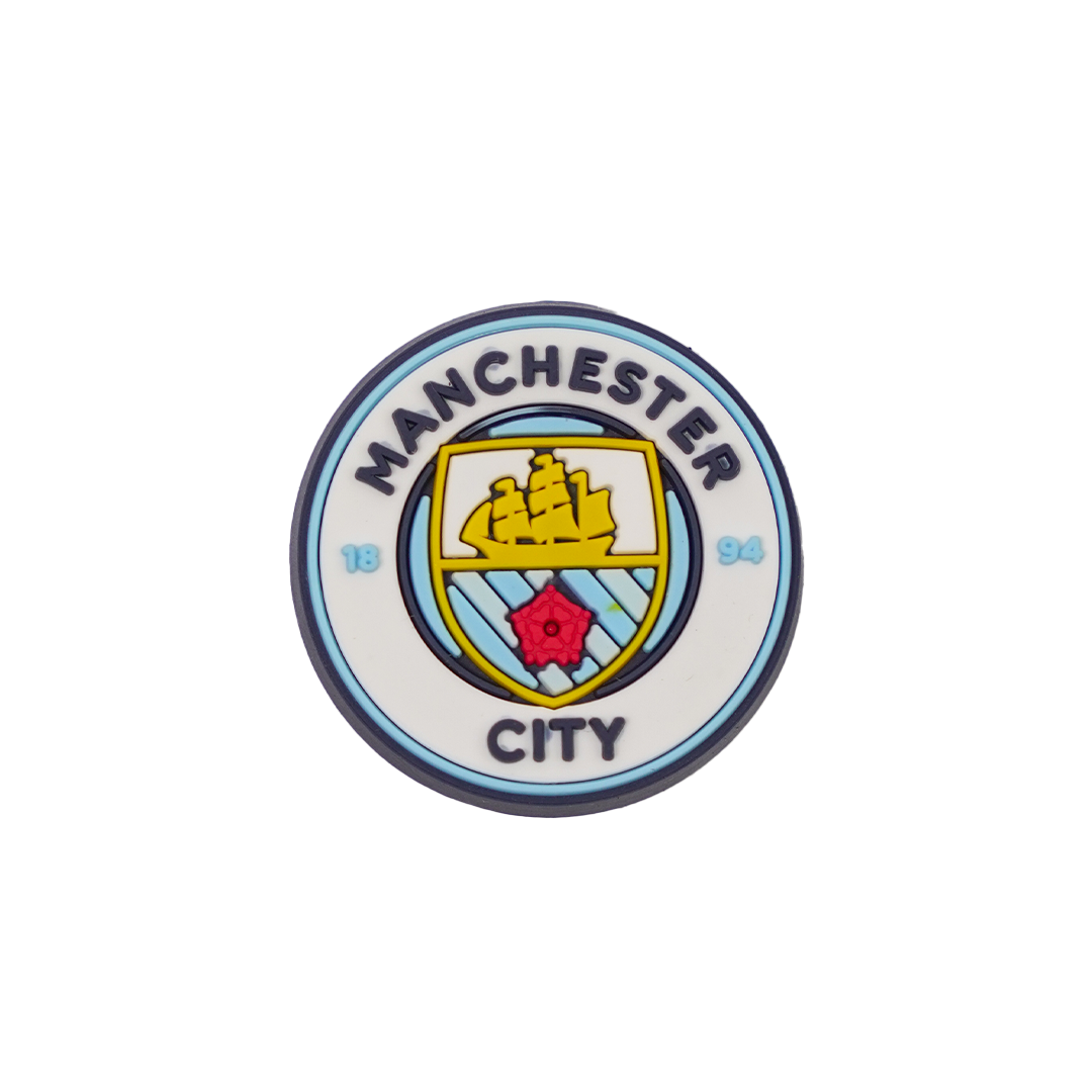 A circular Manchester City Soccer Croc Charm featuring the team's blue and white crest with a gold ship and a red rose.