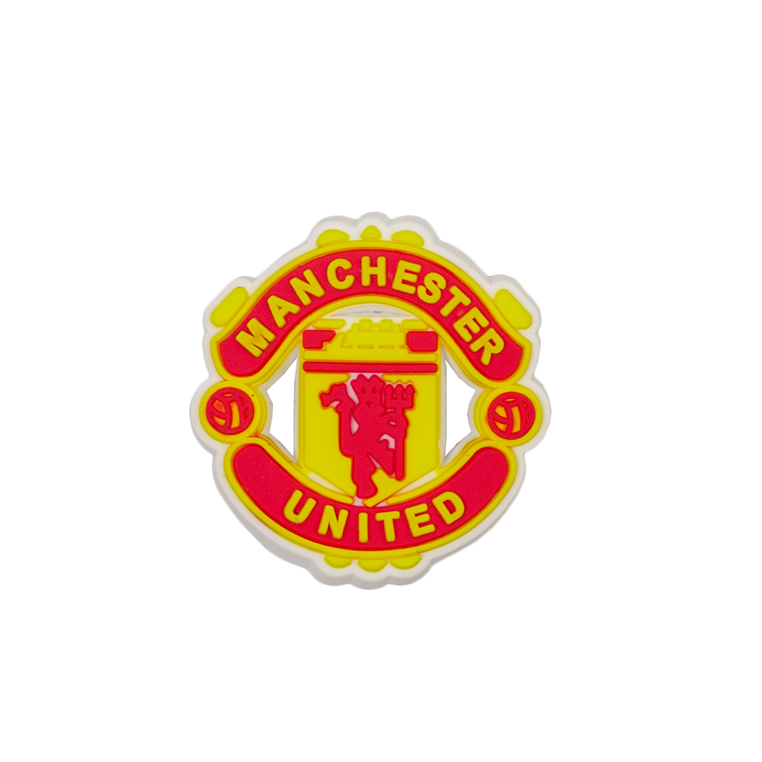 A red and yellow Soccer Croc Charm featuring the Manchester United club crest, with the iconic red devil symbol at the center.