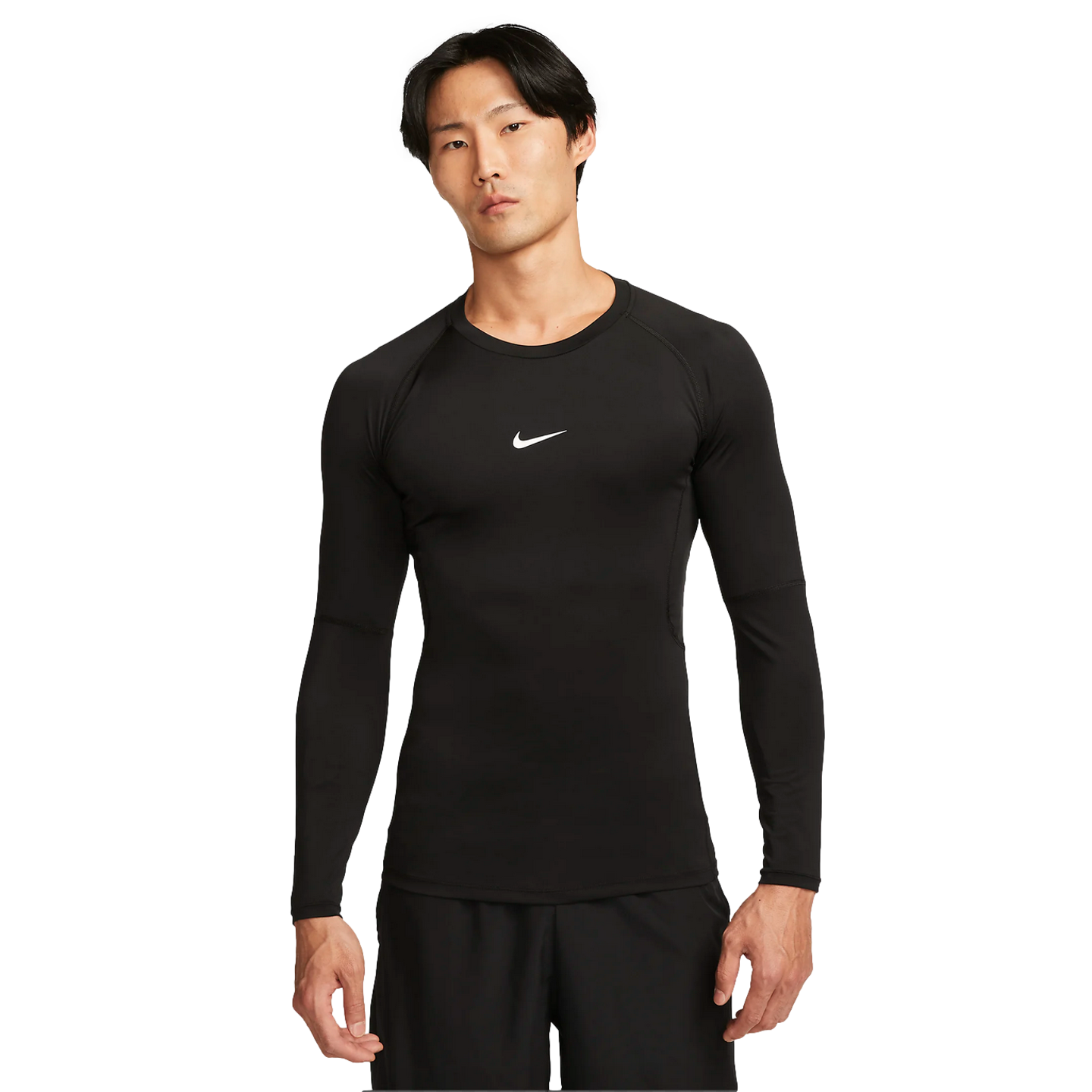 A man wears a black long-sleeved Nike Pro compression top with a white swoosh logo and black shorts, standing against a plain white background.