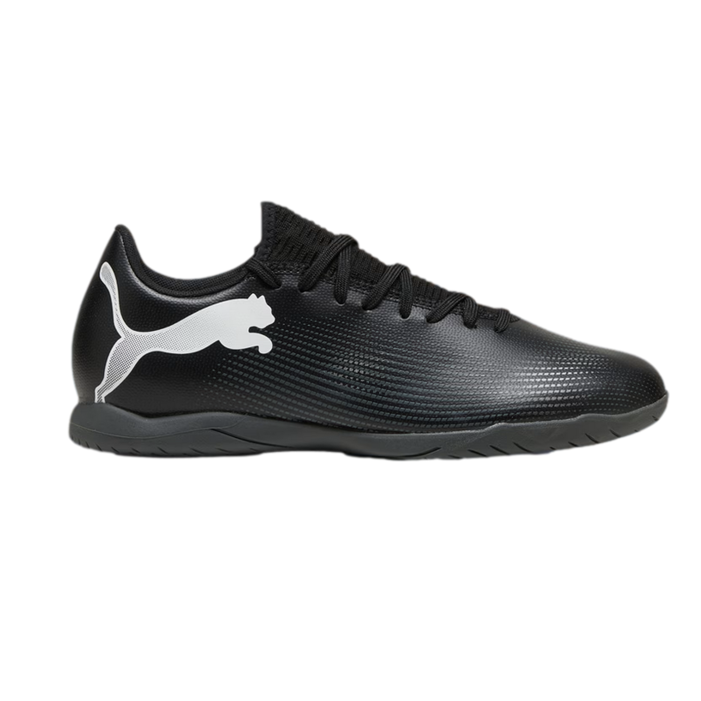 Profile view of a black Puma indoor soccer shoe with a large white logo on the side and a flat rubber sole.