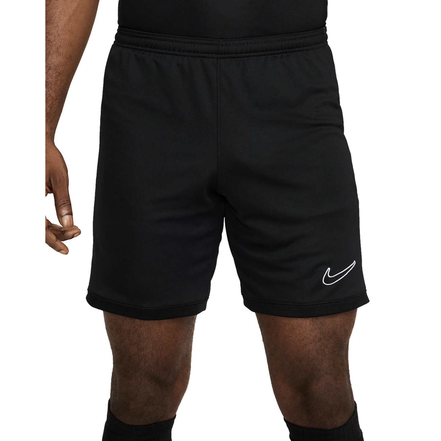 A person wearing black Nike athletic shorts featuring a white swoosh logo on the left leg and a textured mesh hem.