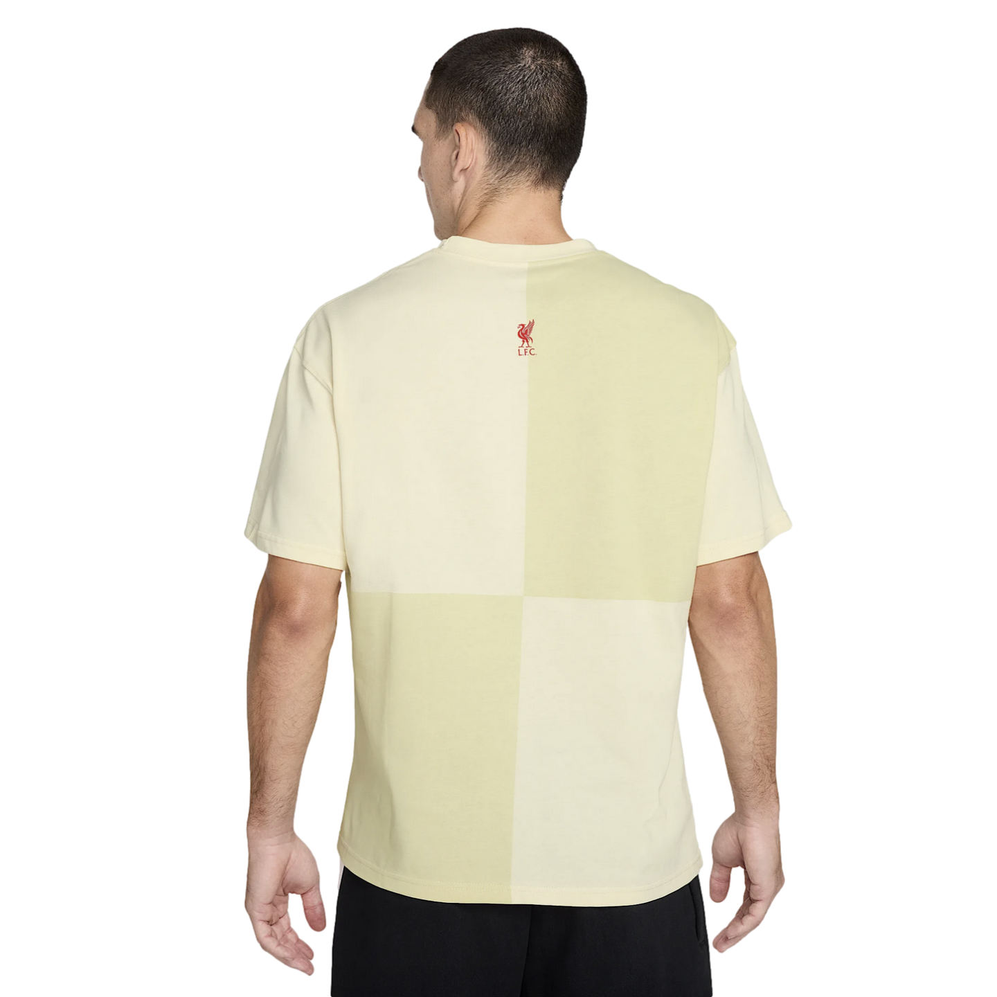 Back view of a man wearing a pale yellow color-block t-shirt with a small red Liverpool FC logo on the upper back.