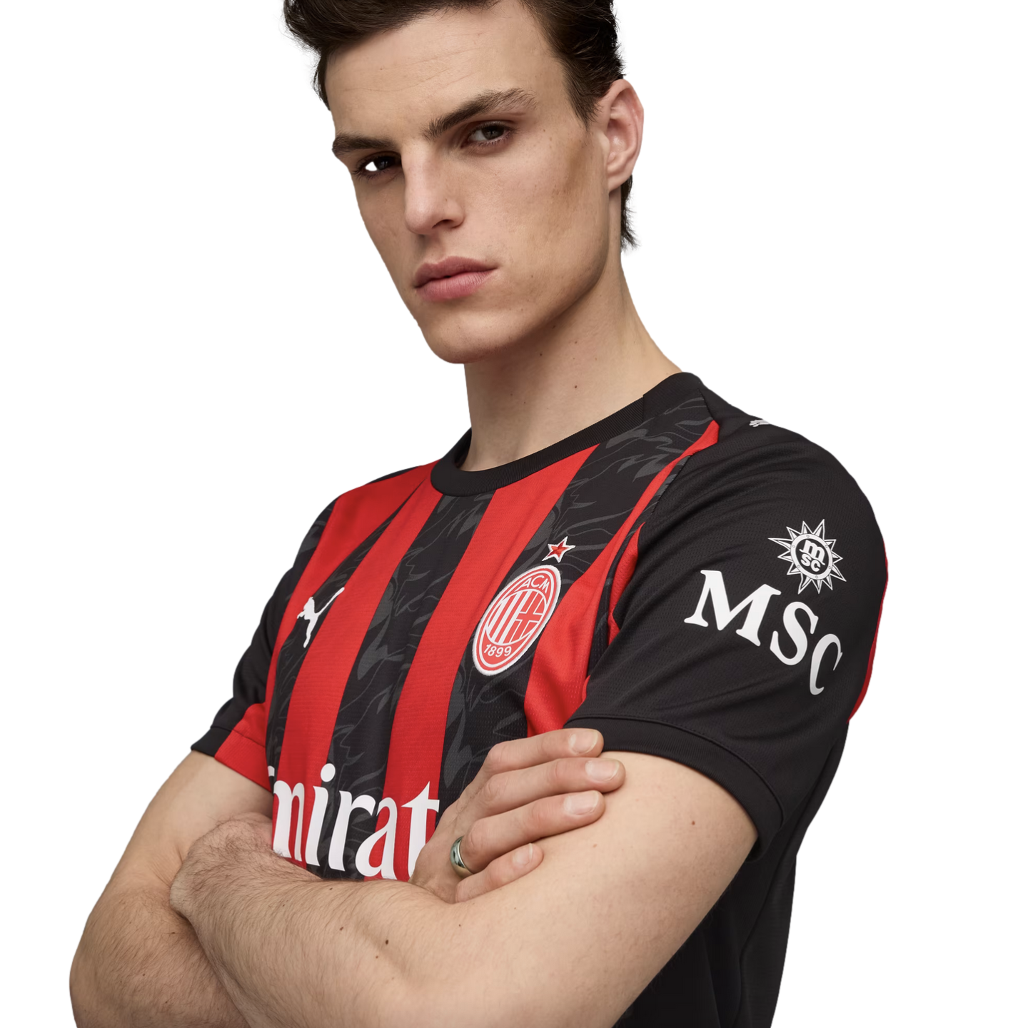 A man in a red and black AC Milan football jersey poses with his arms crossed against a white background.