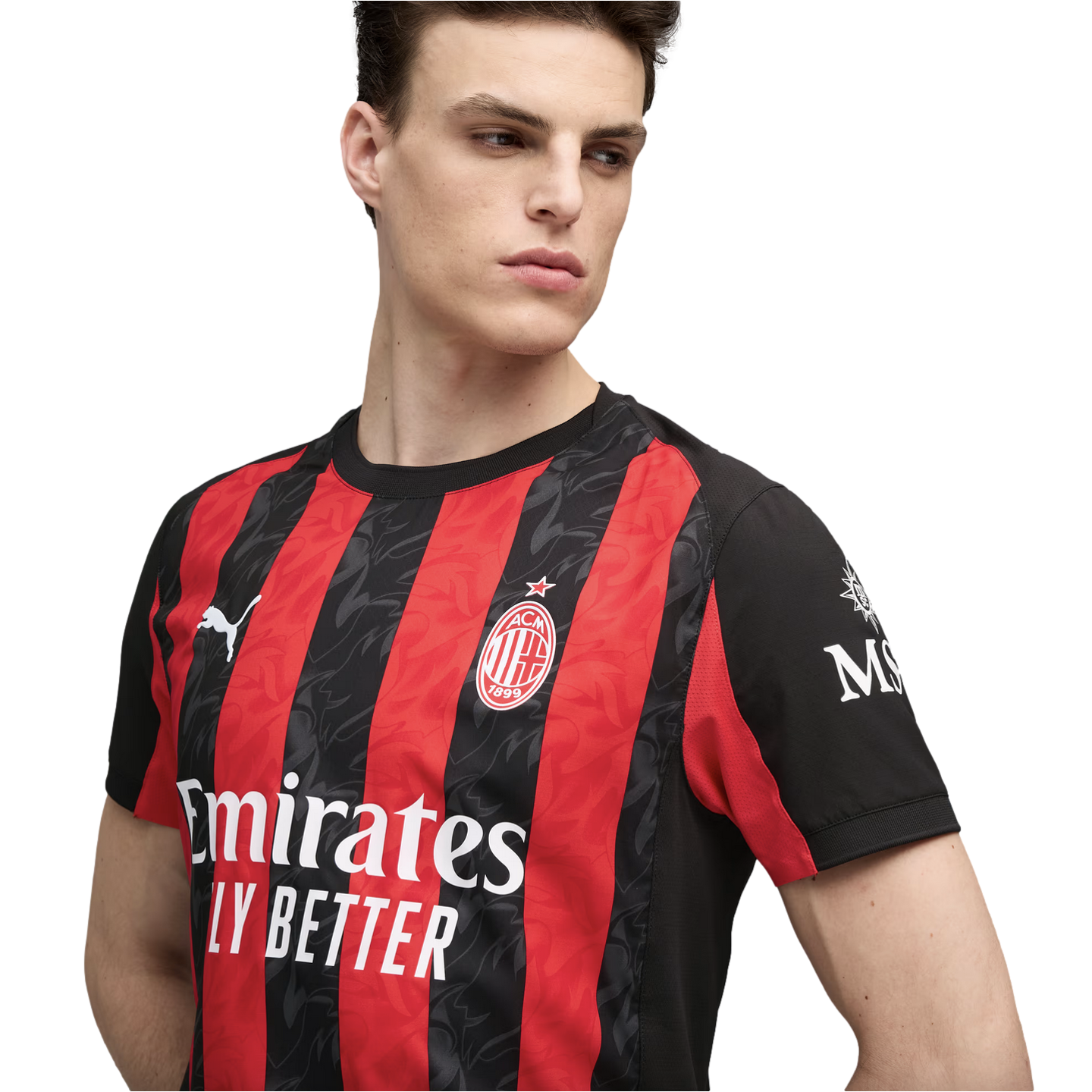 A young man models the red and black striped AC Milan home jersey, featuring the club crest and sponsor logos.