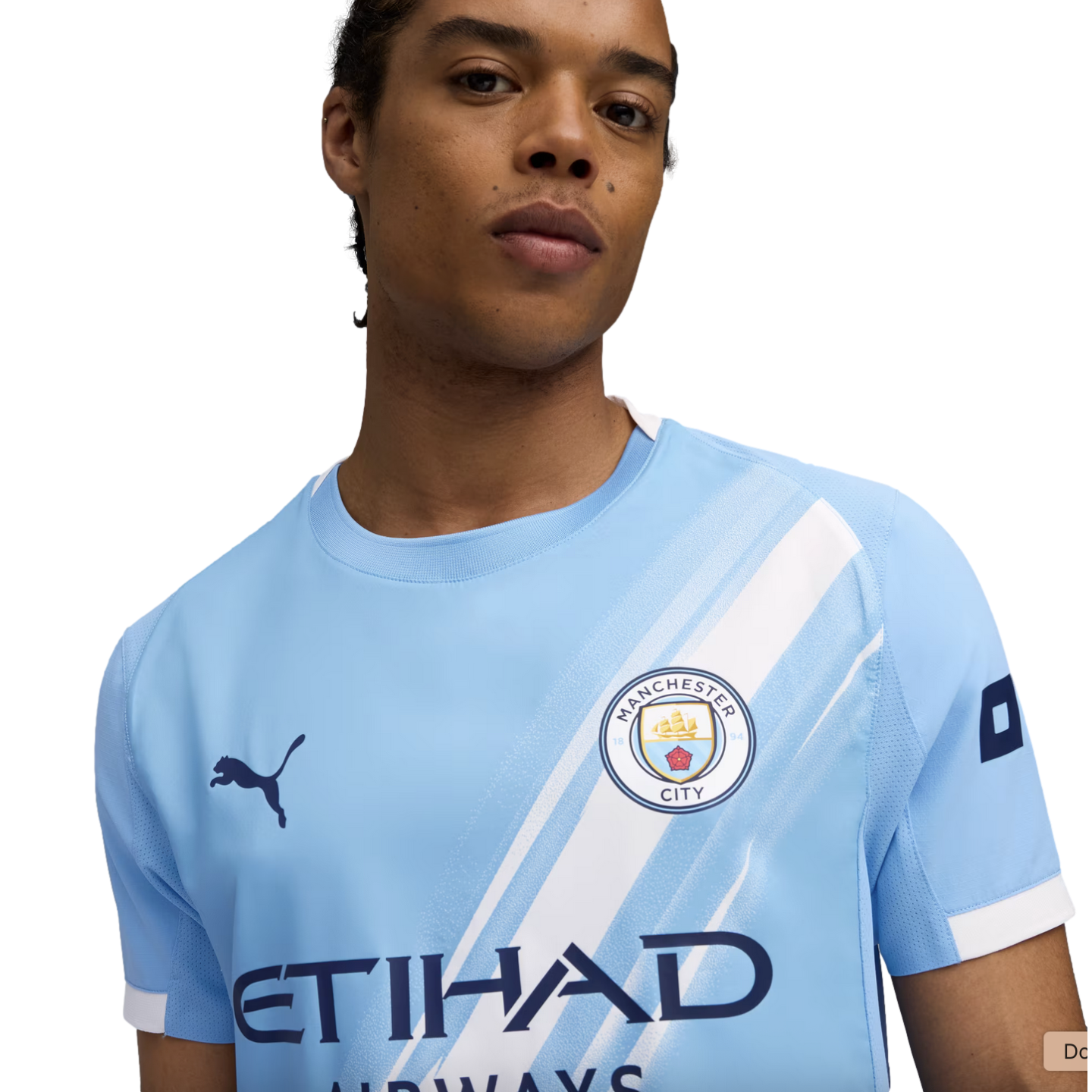 A person wearing a light blue Manchester City football jersey with a white diagonal sash, the club crest, and a Puma logo.