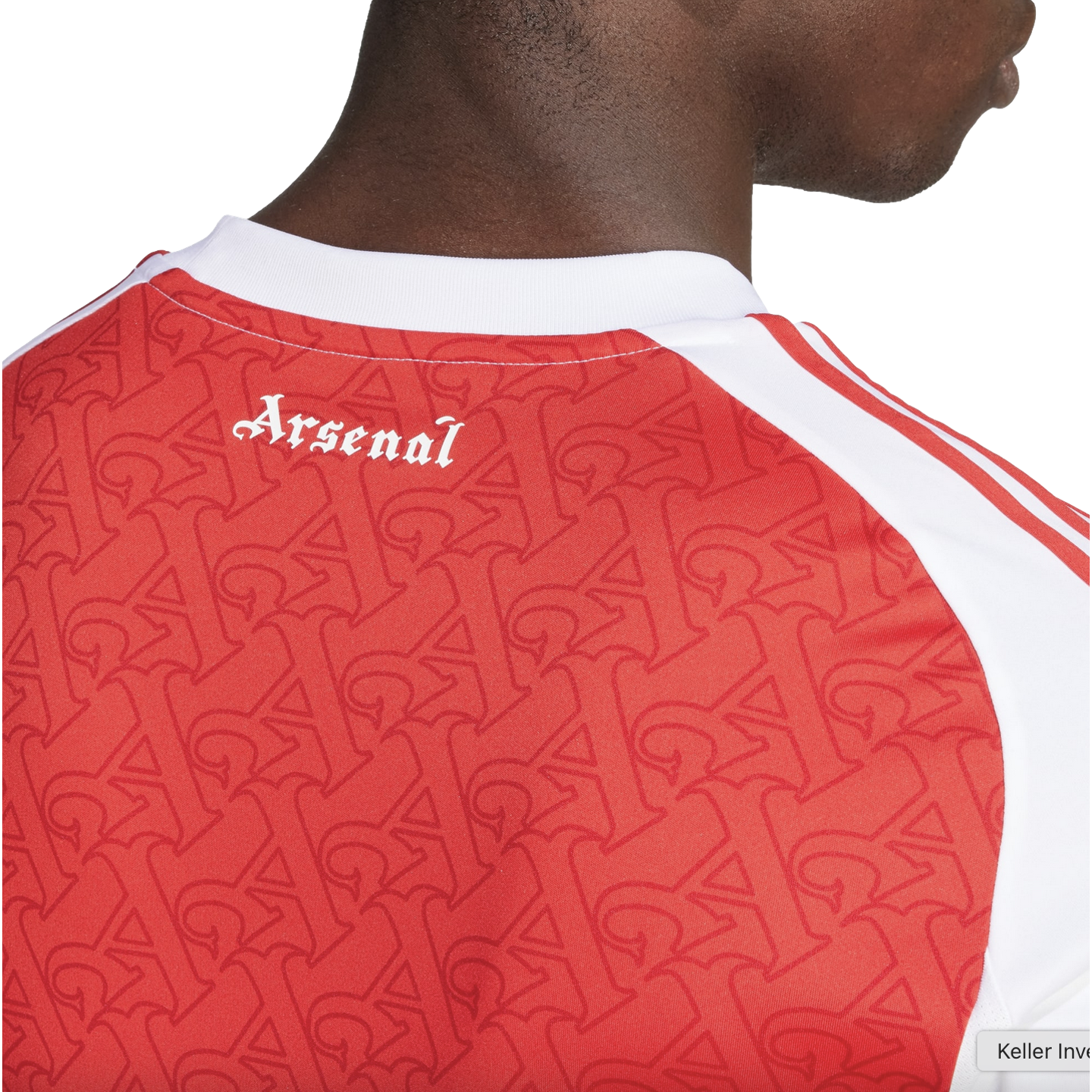 Close-up of the back of a red Arsenal jersey with white gothic-style text reading "Arsenal" and a repeating "A" monogram pattern across the fabric.