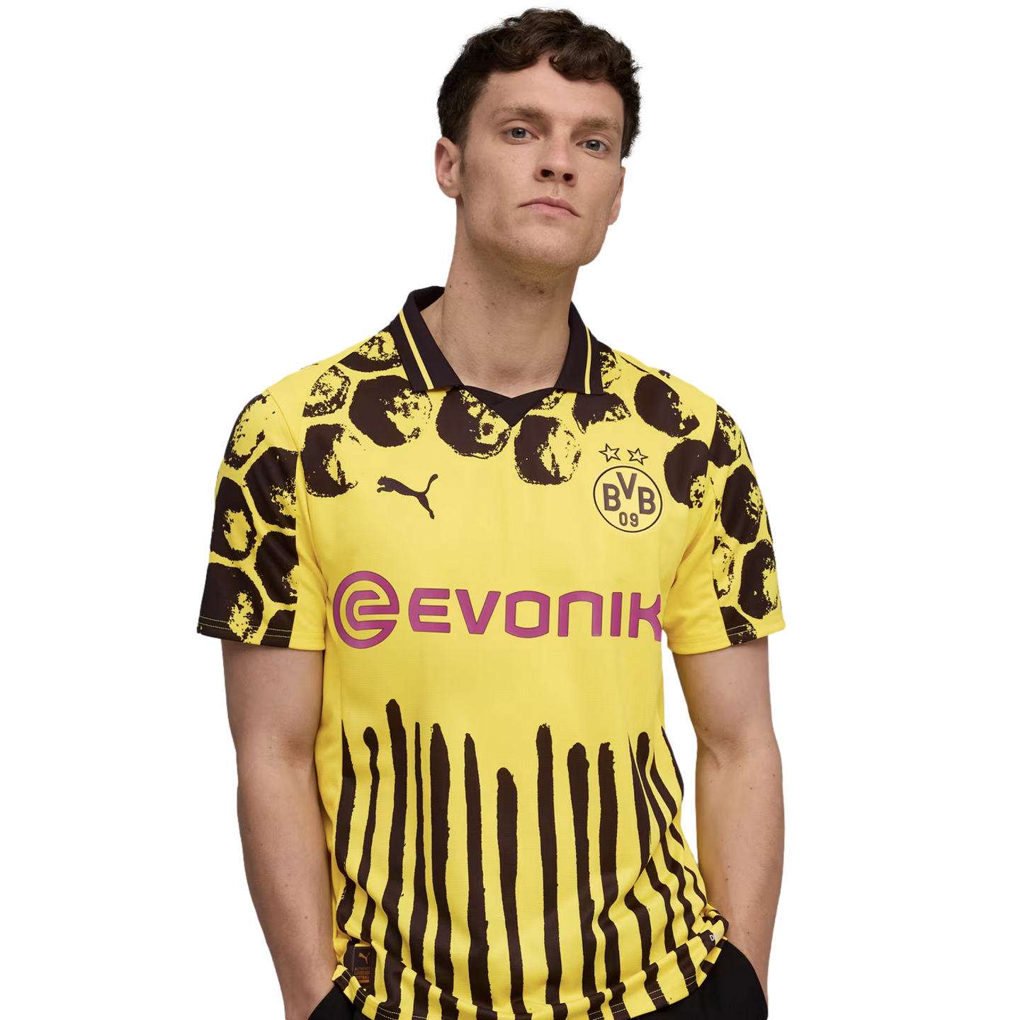 A man wearing a yellow and black Borussia Dortmund soccer jersey with animal-print spots and vertical stripes, featuring the Evonik sponsor logo, against a white background.