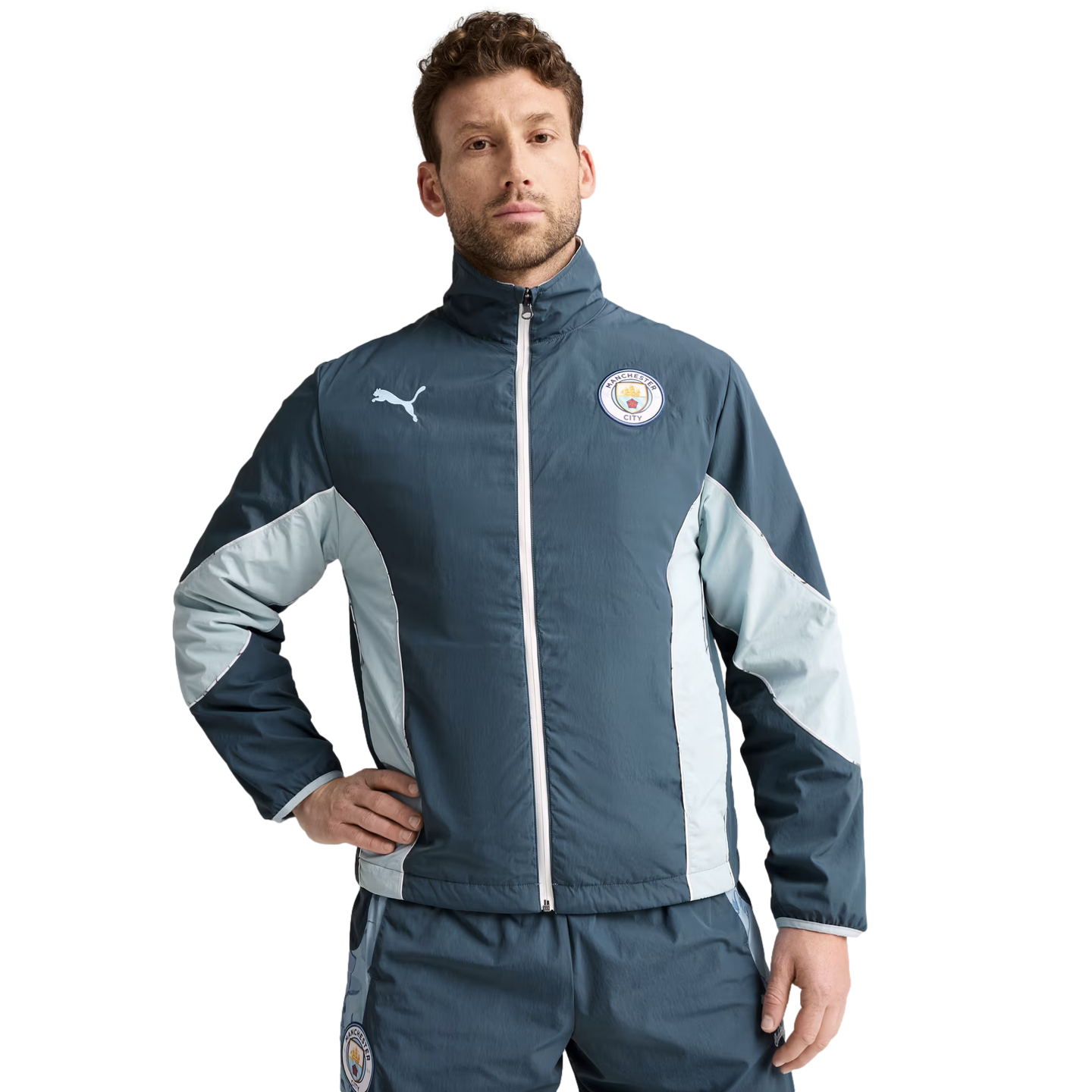 A man wearing a blue and light-blue Puma track suit featuring the Manchester City F.C. crest.