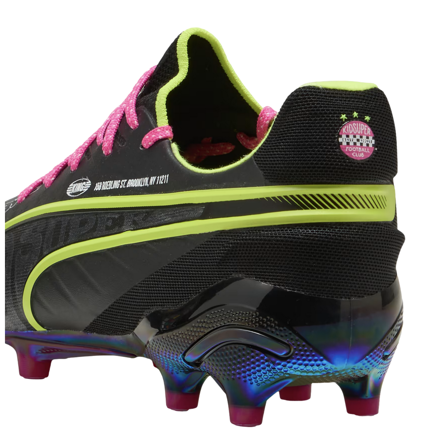 Black Puma soccer cleat with neon green accents, pink laces, and an iridescent blue sole. The heel displays a pink Kidsuper logo. Viewed from the rear.