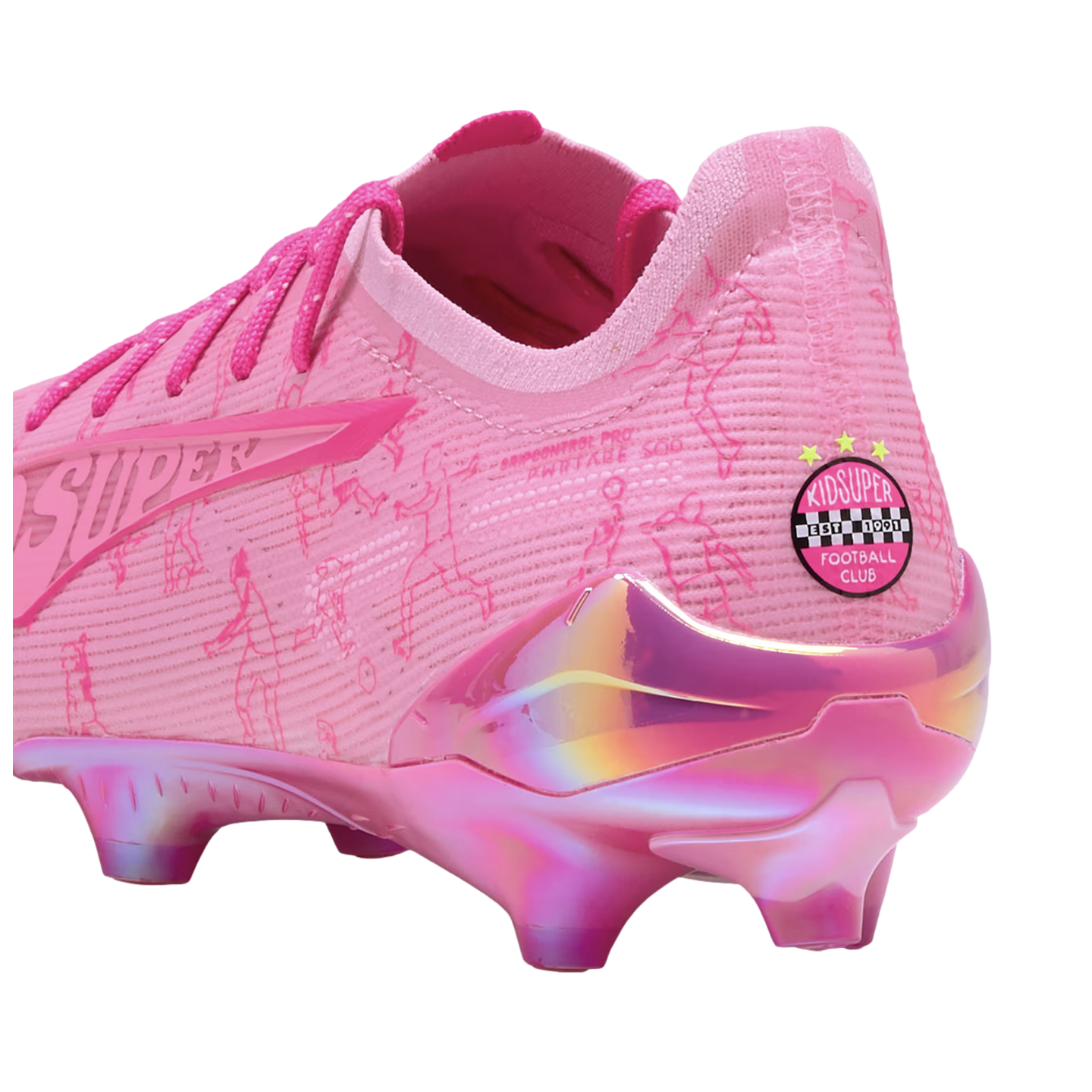Bright pink soccer cleat with iridescent metallic accents, "KIDSUPER" branding on the heel, and doodle-like line drawings on the fabric upper.
