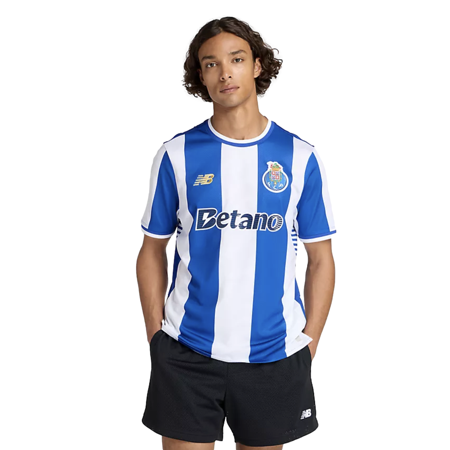 A man with curly hair wears a blue and white striped FC Porto soccer jersey and black shorts against a plain white background.